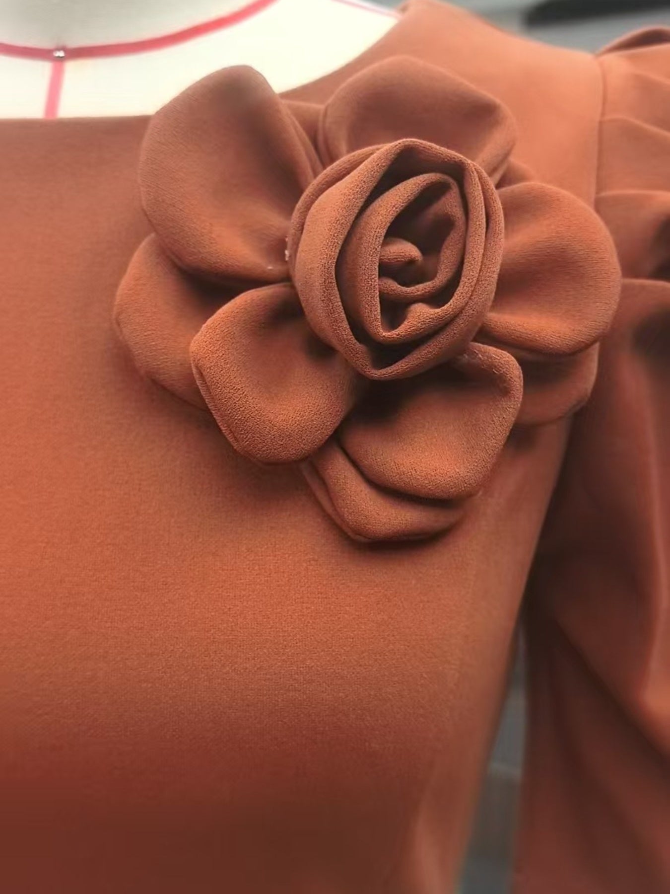Close up detail of a light brown bodycon midi dress rose applique on the bodice