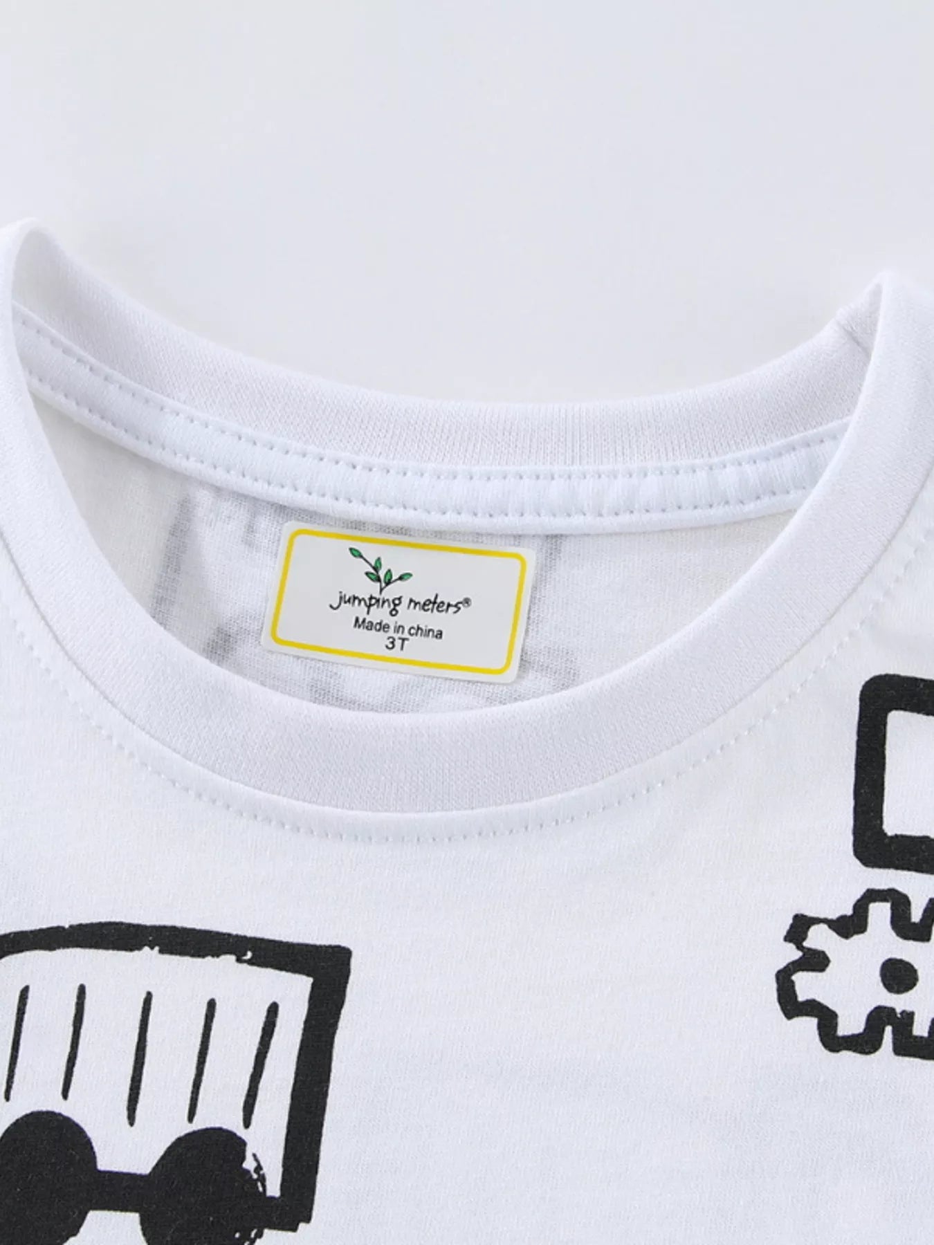 Close-up of the white crew neckline and label above black construction vehicle prints