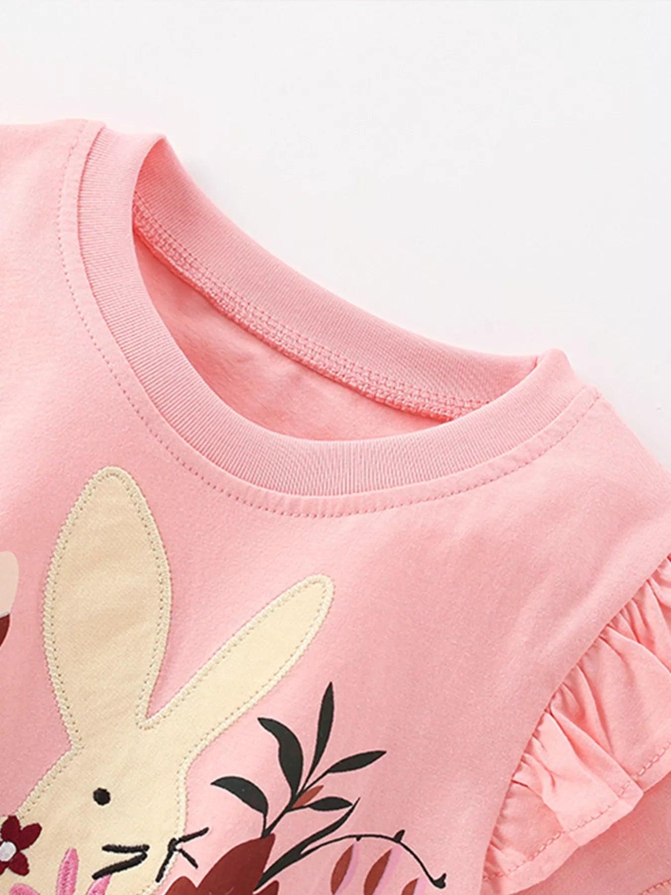 Close-up of blush pink children's t-shirt neckline, bunny ears and ruffle sleeve edge