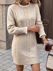 On model side view of beige cable knit sweater dress with white lace cuffs and ribbed hem