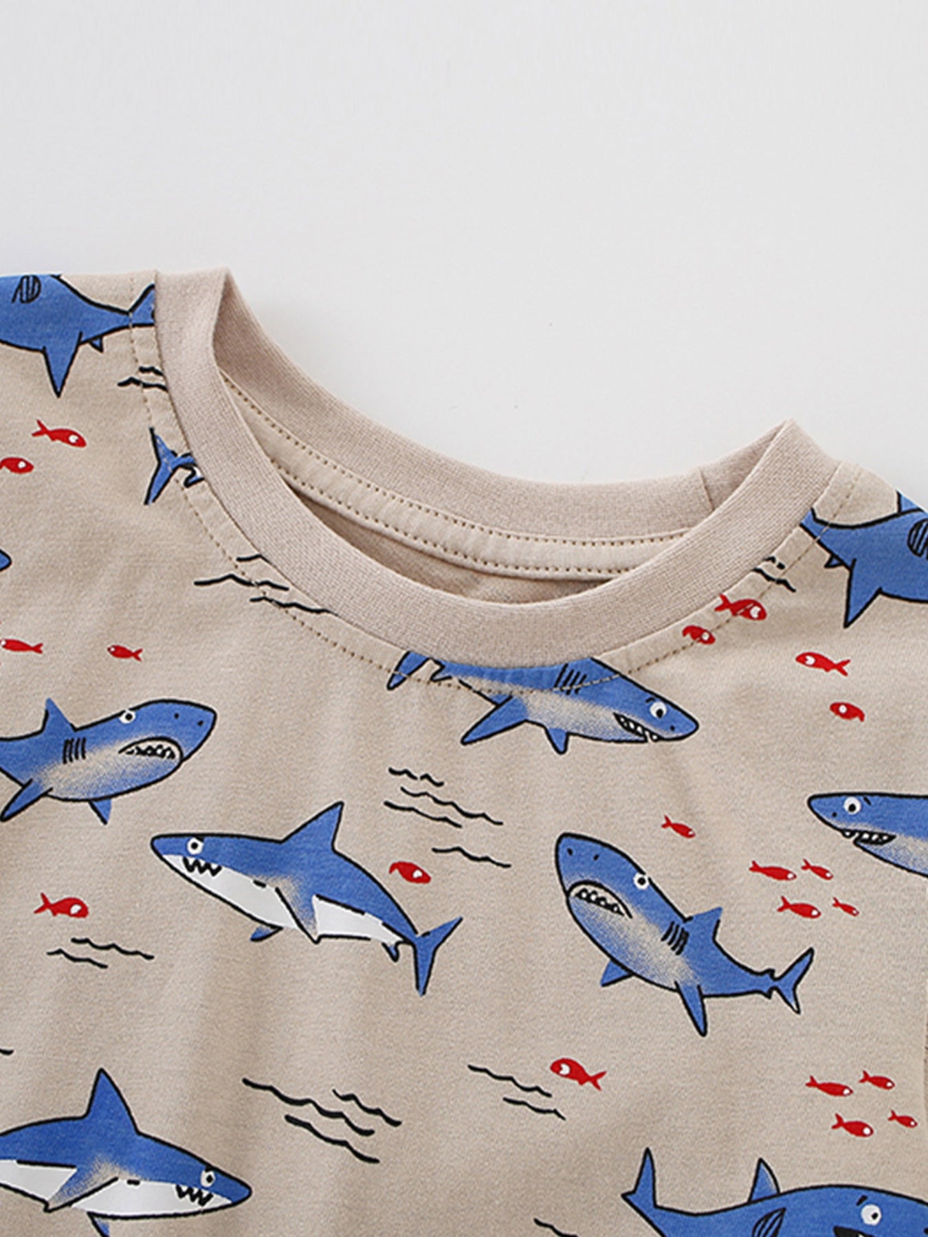 Detail view of the ribbed crew neckline on a children's shark print t-shirt with blue sharks