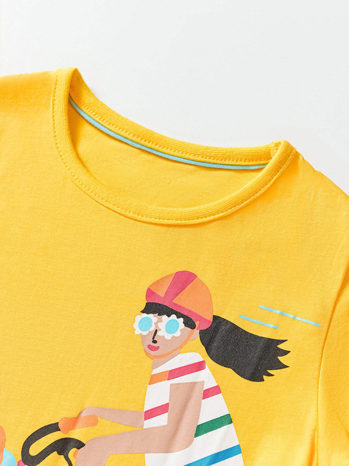 Angled close-up of yellow children's t-shirt collar and cyclist graphic upper detail