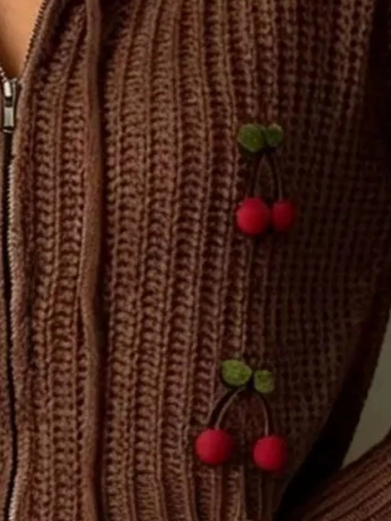 Close up of brown knit zip up sweater showing ribbed texture and red cherry appliques