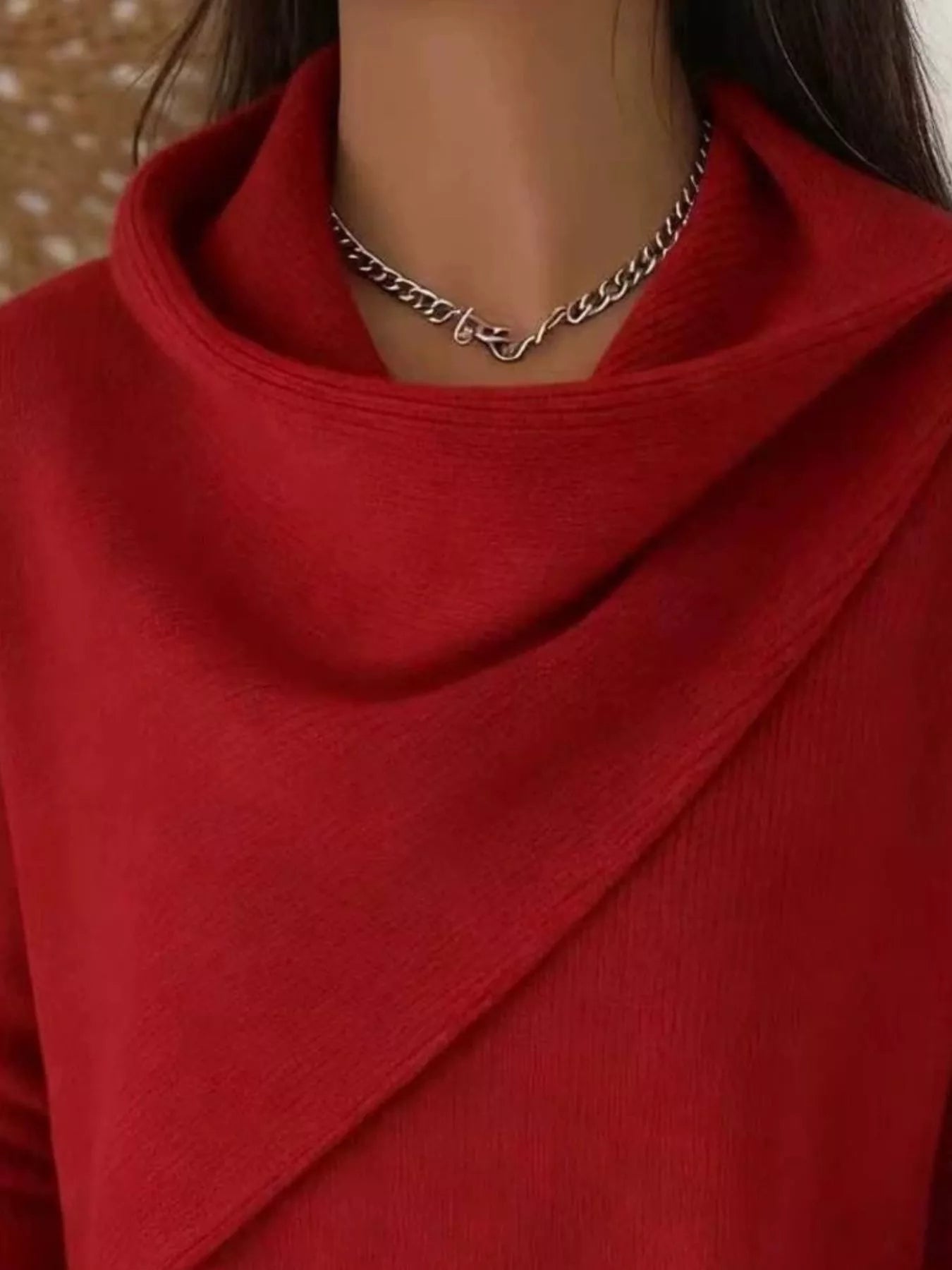Close-up of the red cowl neckline showing the draped asymmetric collar and fine knit texture