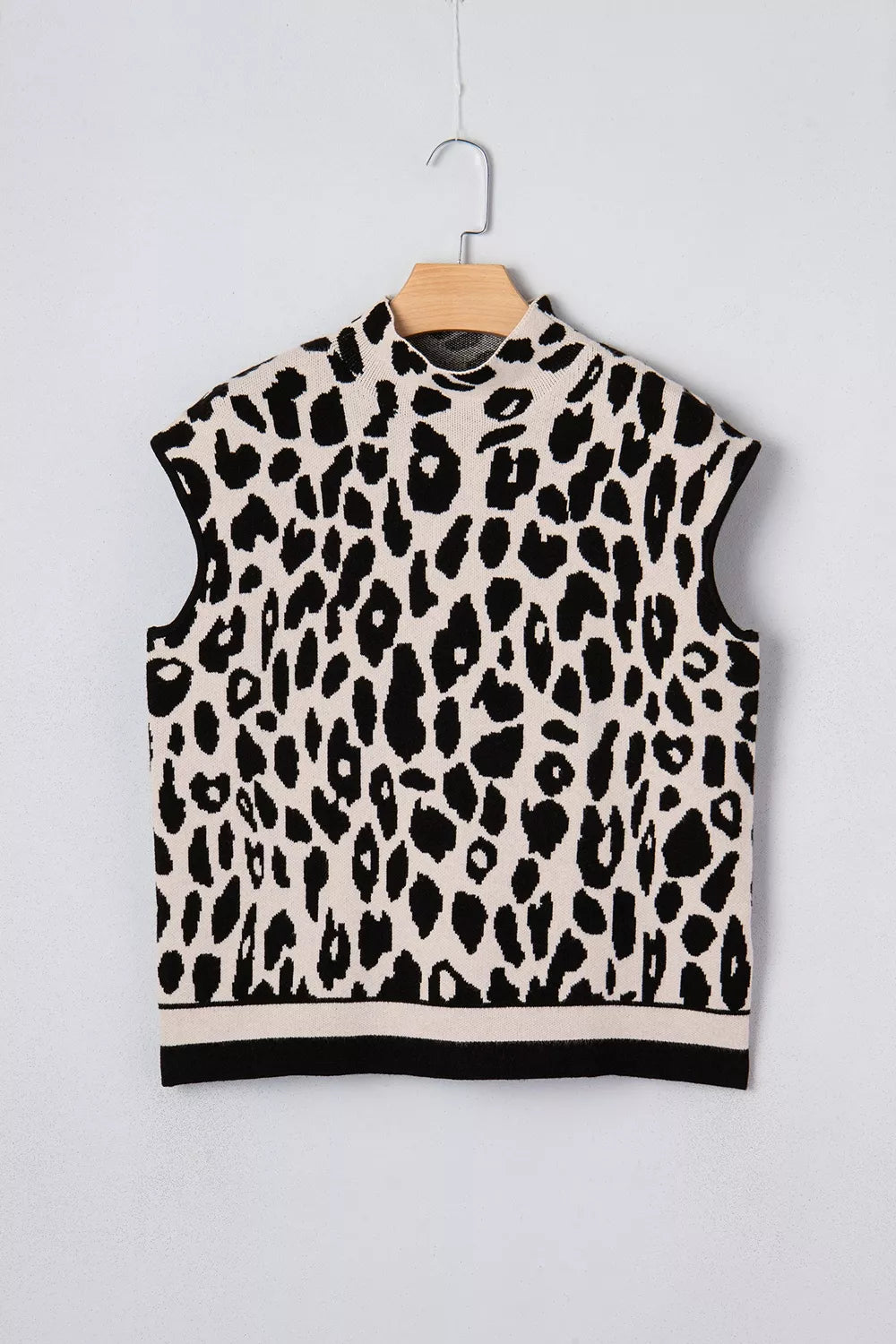 Flat lay front view of the black and cream leopard print high neck sweater on a hanger.