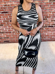 Front view of a plus size black and white sleeveless bodycon maxi dress with a black crossbody bag
