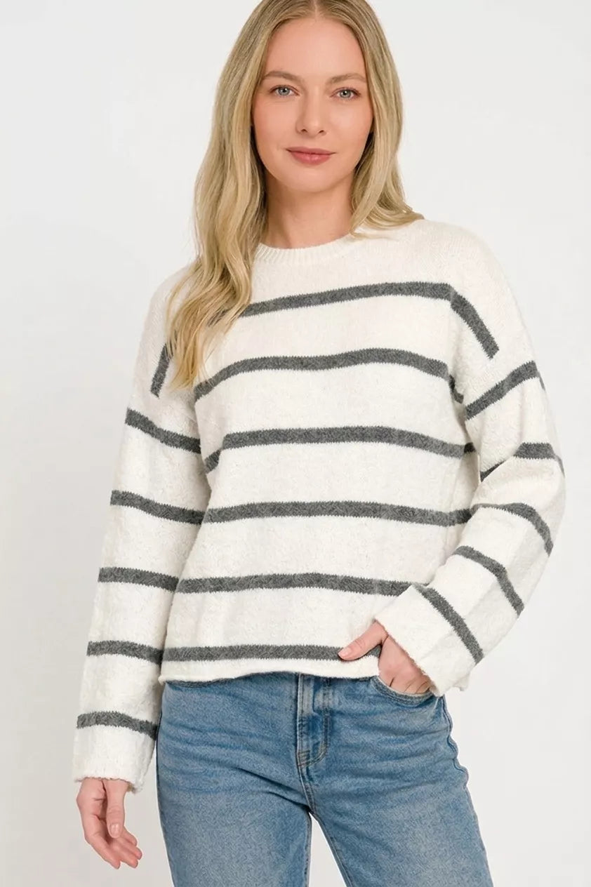Front view of white striped sweater with charcoal horizontal stripes and jeans