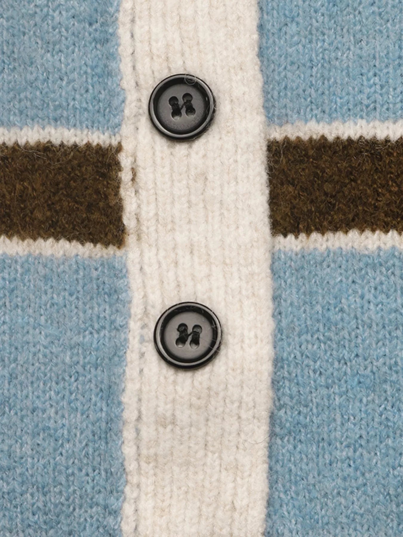 Close up of black buttons on cream placket of striped blue knit sweater.