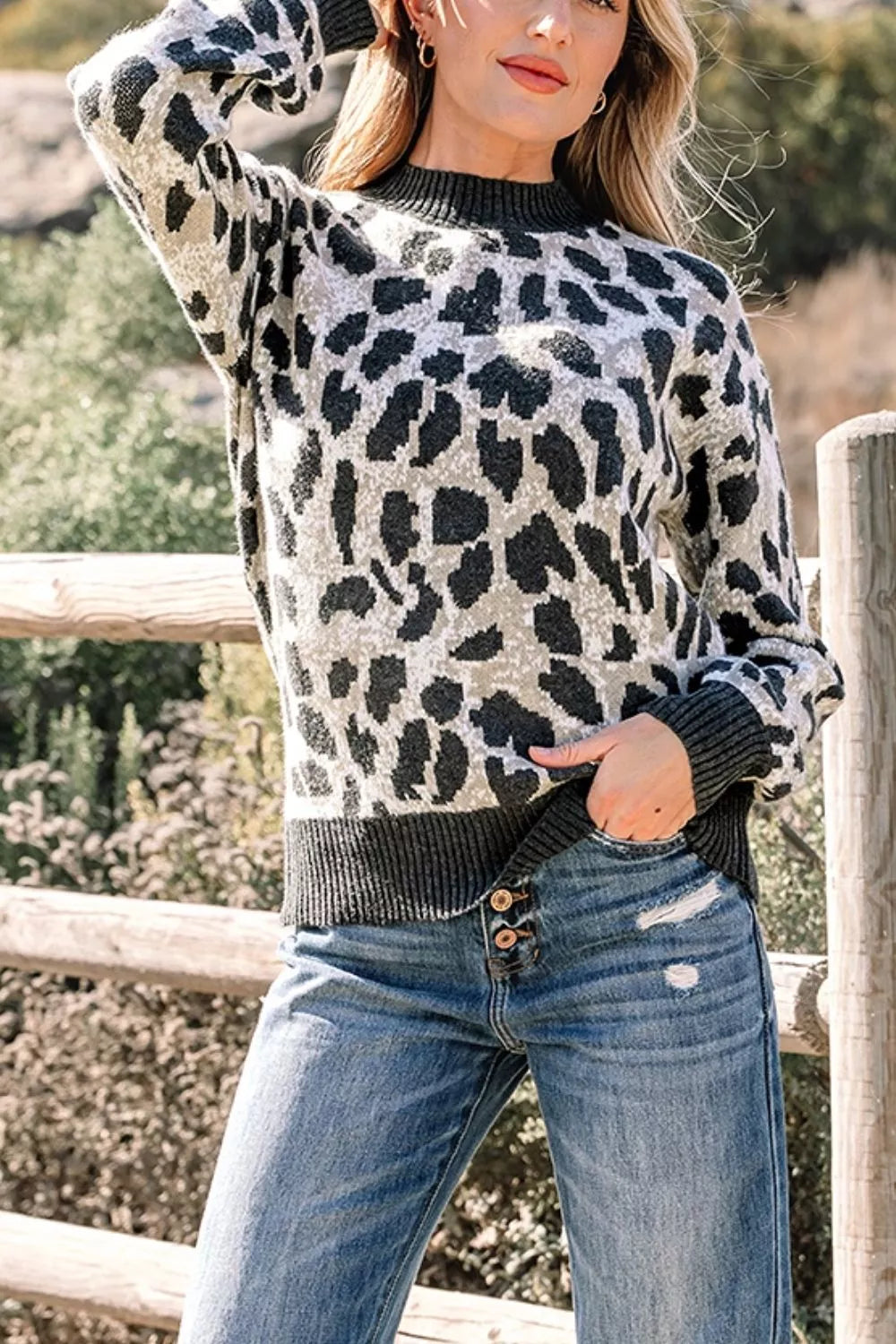 Front view of the gray and black leopard print baggy sweater with ribbed collar, arm raised.