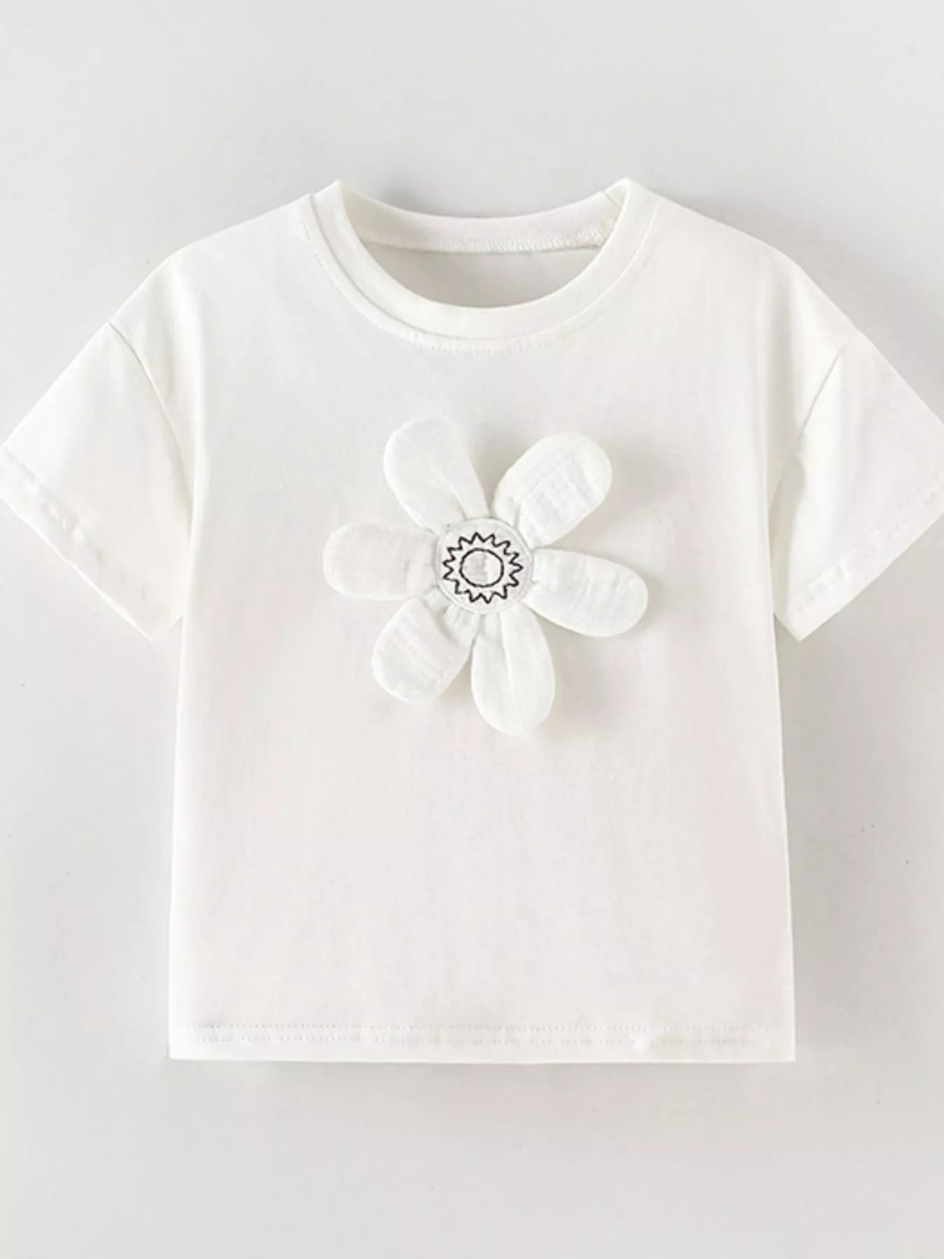 Front view of white children's t-shirt with large padded flower applique and stitched center