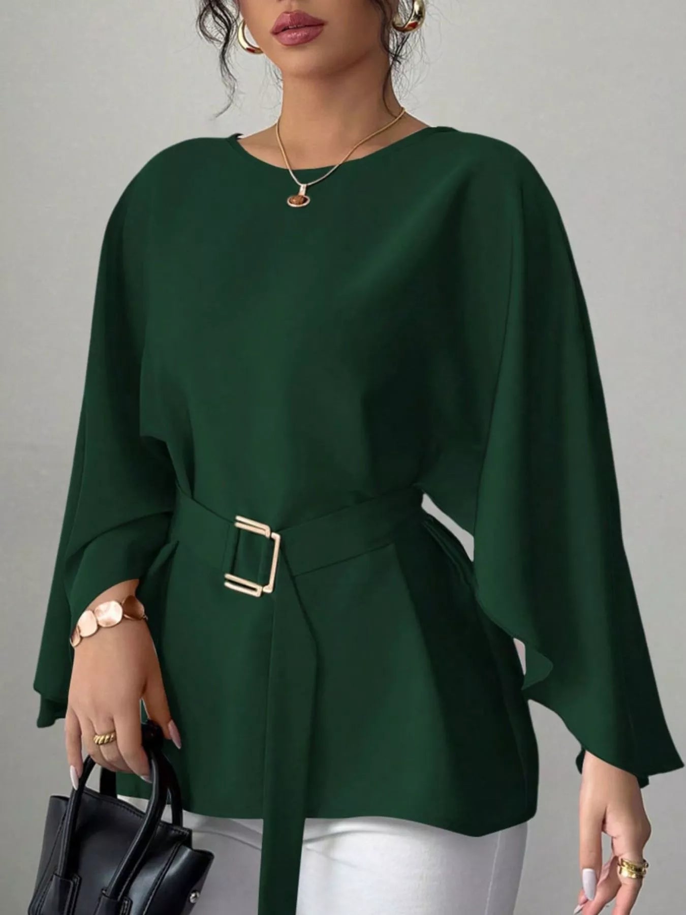 Dark green round neck blouse front view holding black handbag with gold buckle belt