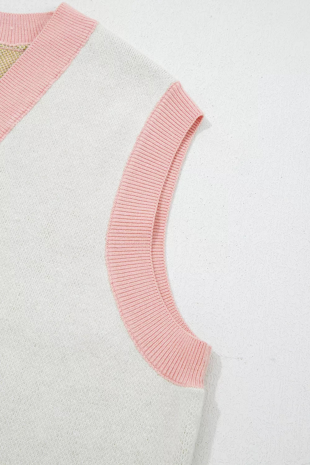 Close-up of the pink ribbed armhole trim on the cream sweater vest