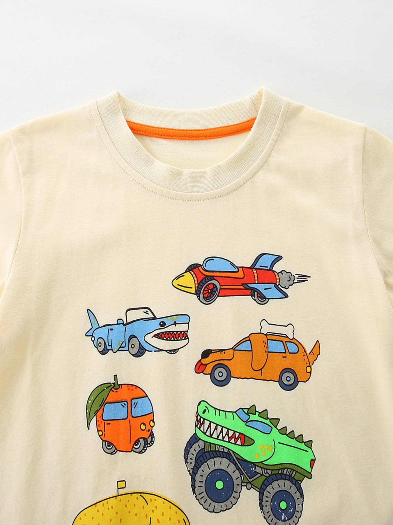 Close-up of the cream crew neckline with orange trim and upper cartoon car prints