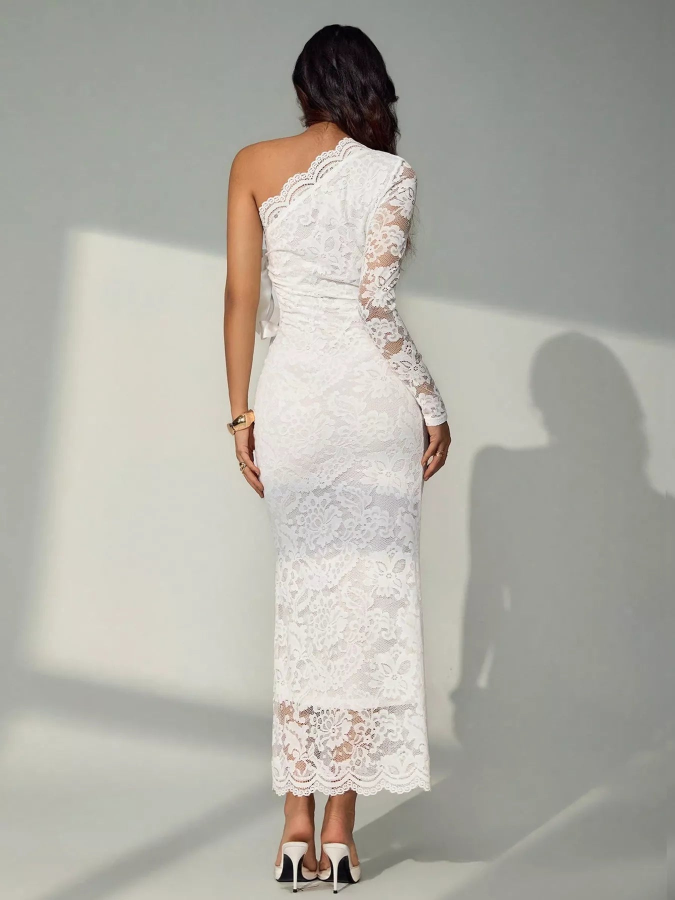 Back view of a white lace one shoulder midi dress with a long lace sleeve