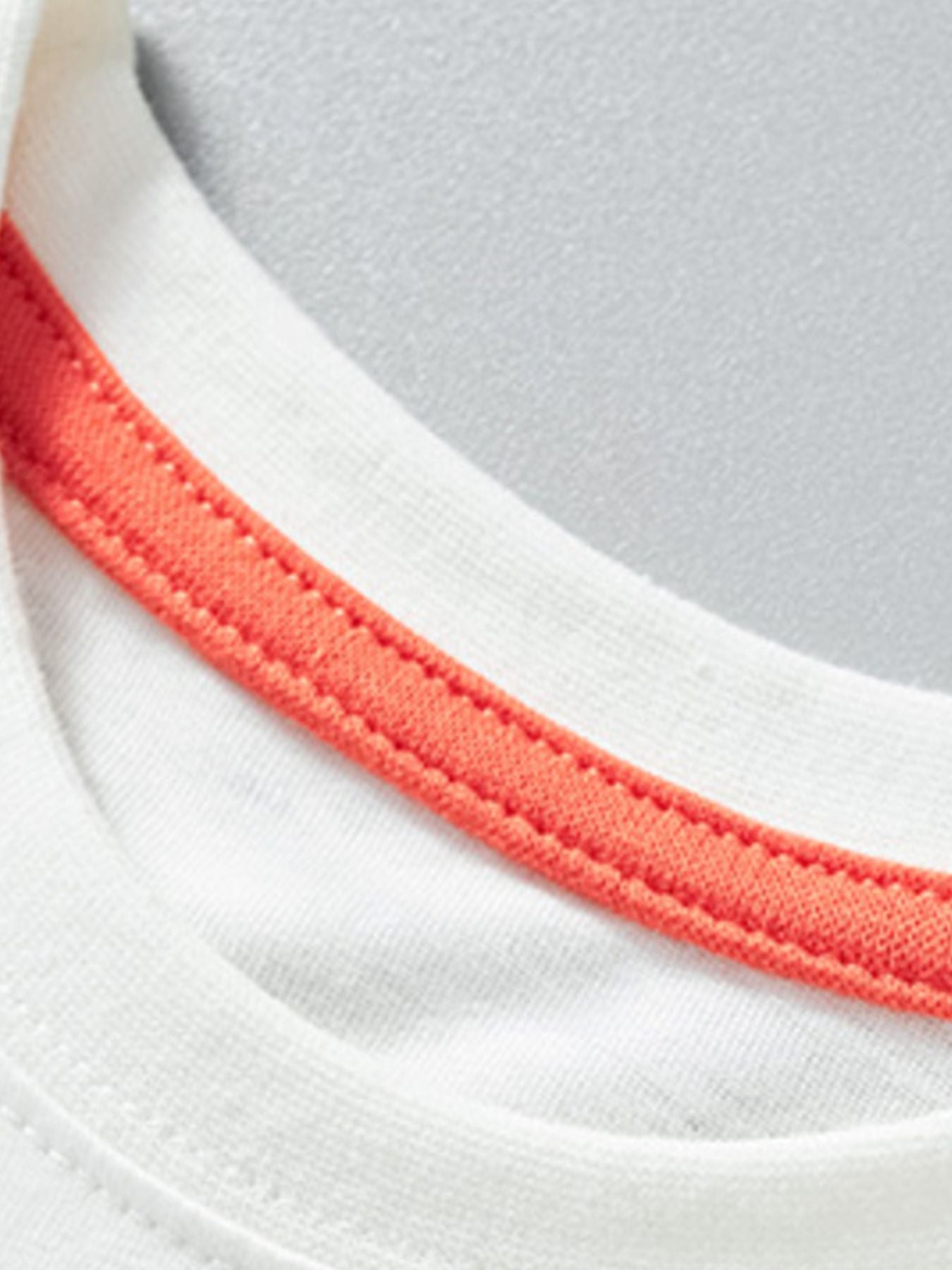 Close view of the white round neckline with coral inner trim on the children's t-shirt