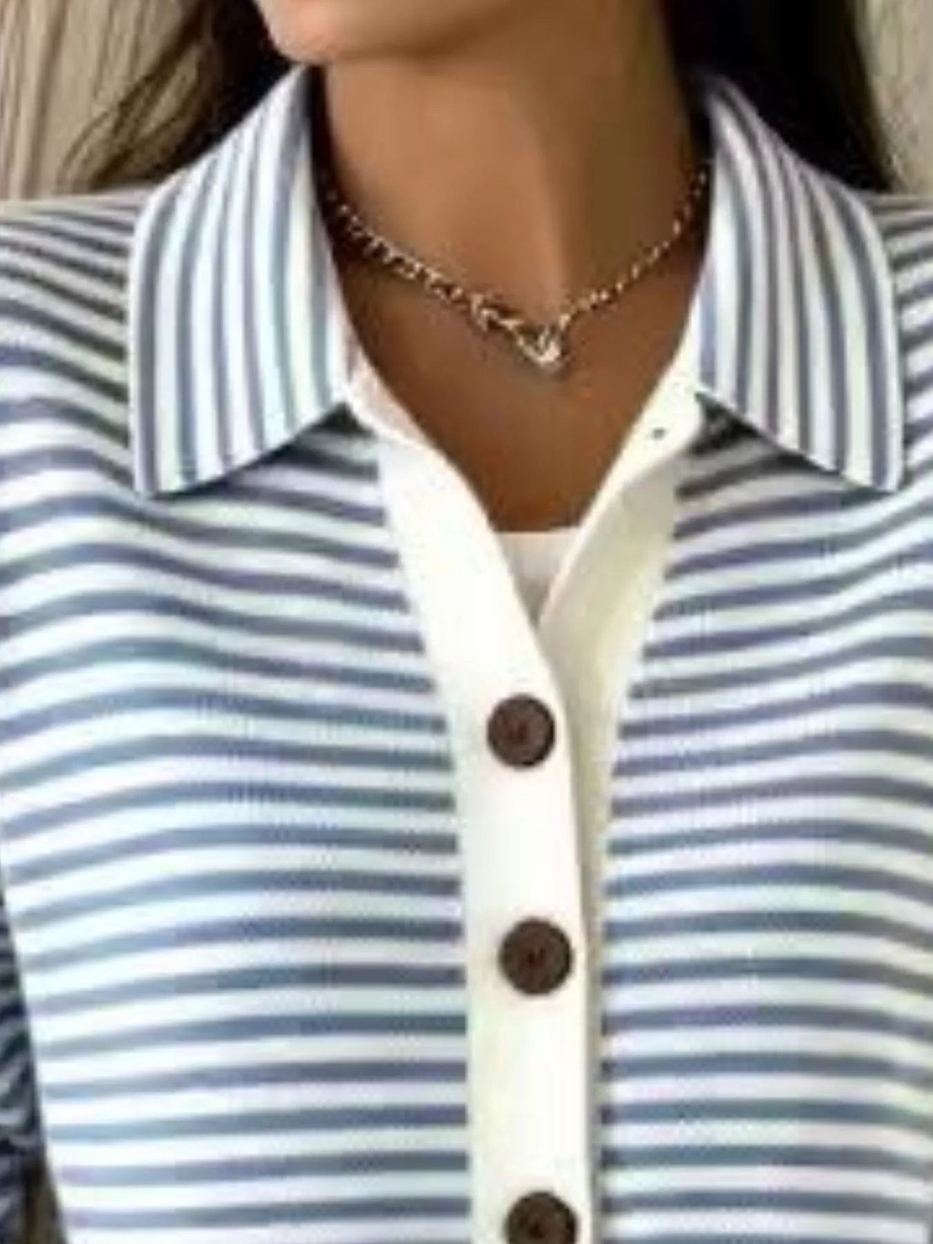 Close-up of the collar and brown buttons on a blue and white striped knit cardigan