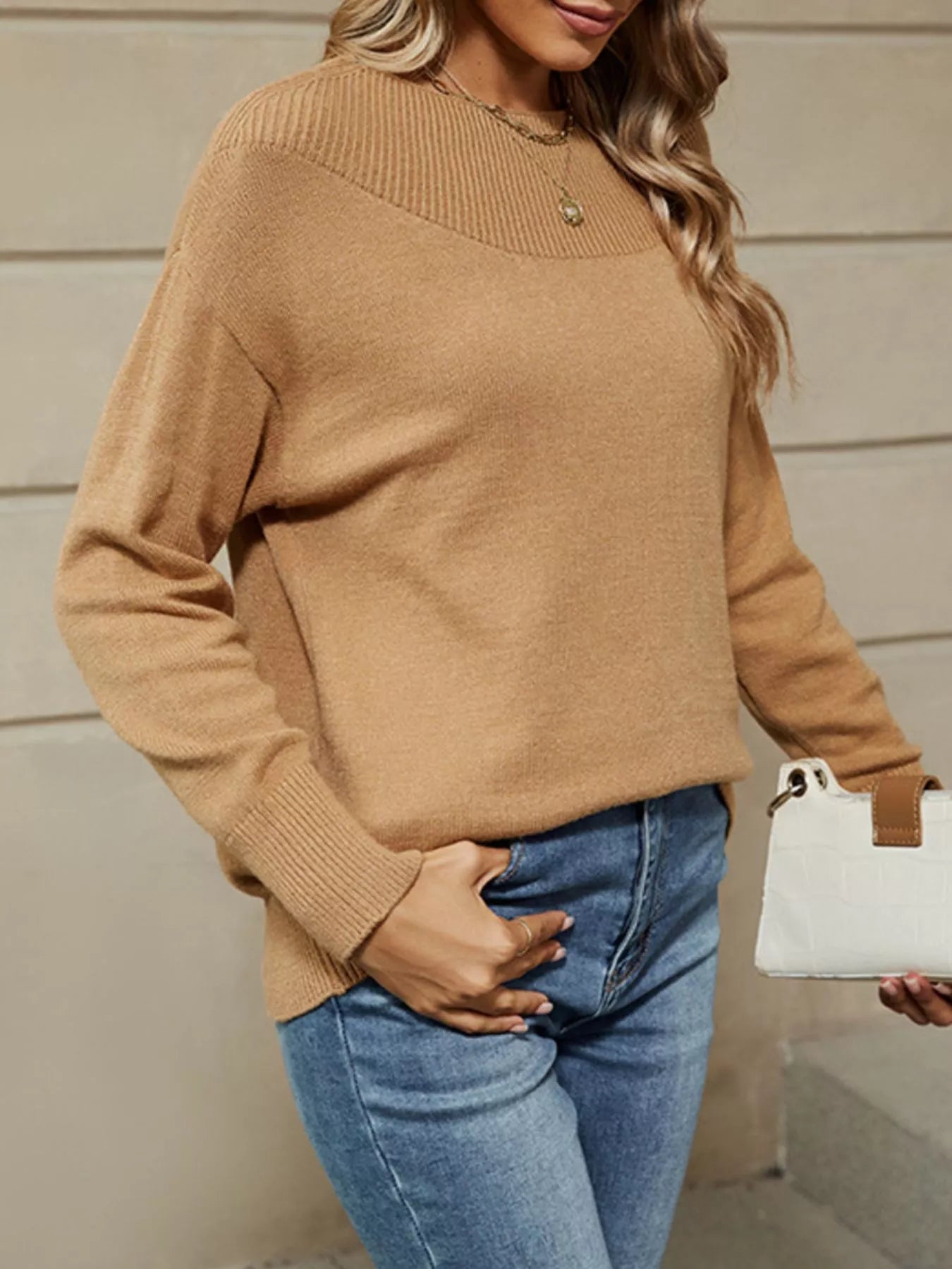 Standing side view of the camel dropped shoulder sweater with a ribbed yoke and jeans