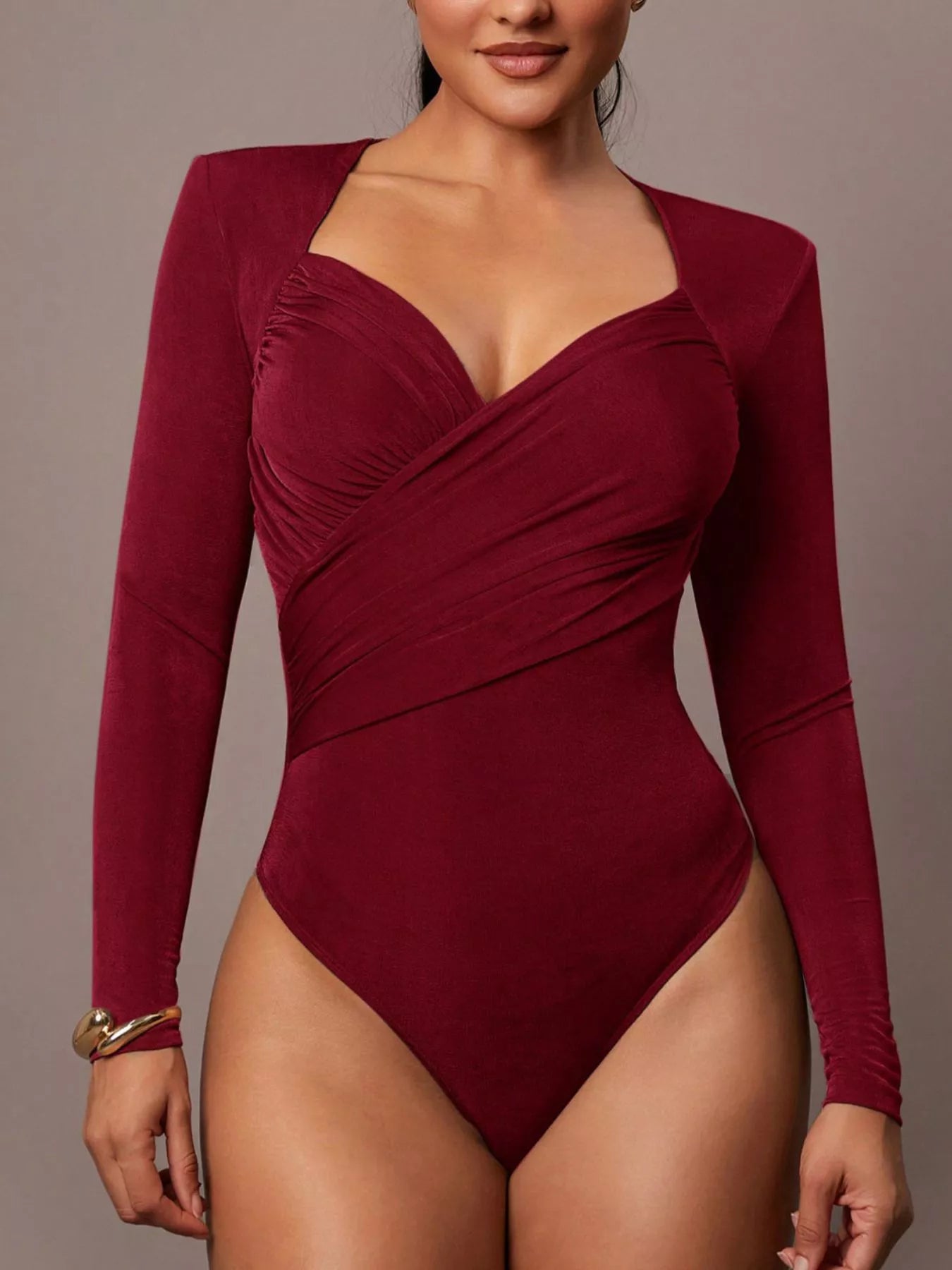 Model wearing burgundy ruched surplice long sleeve bodysuit in front view