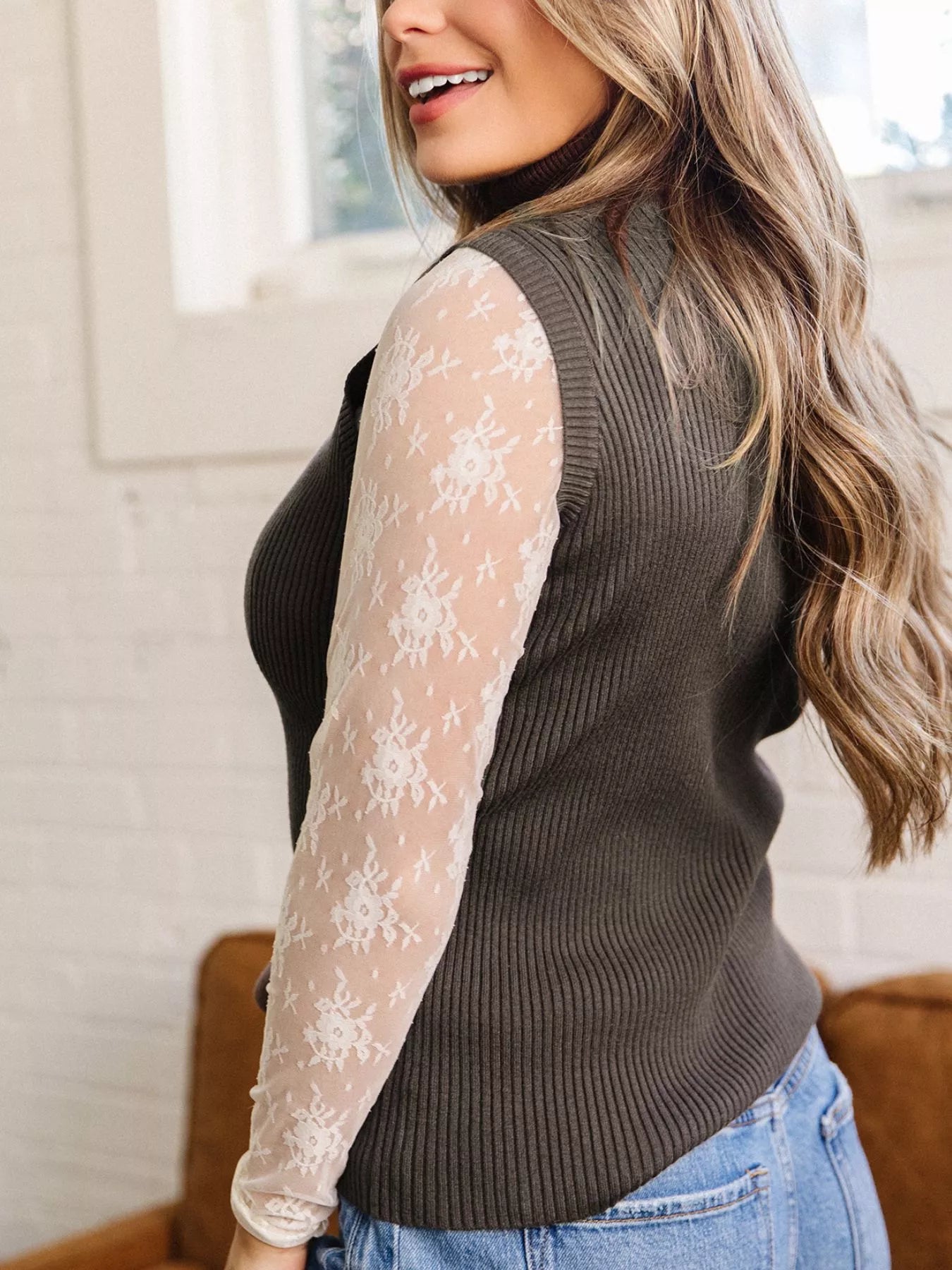 Side view of coffee brown ribbed high neck sweater vest over lace top