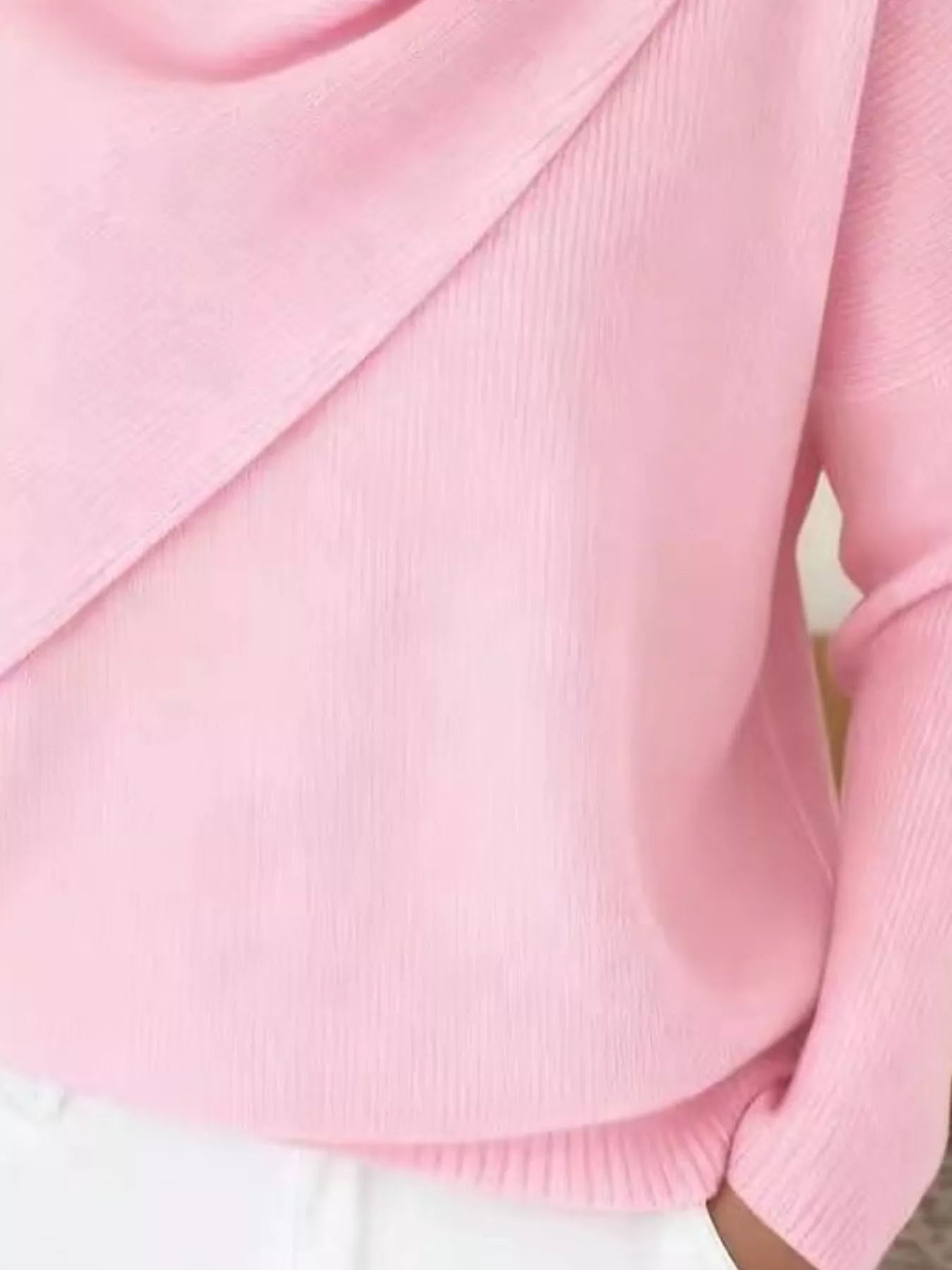 Close-up of the pink sweater lower body and long sleeve showing the ribbed hem and knit texture