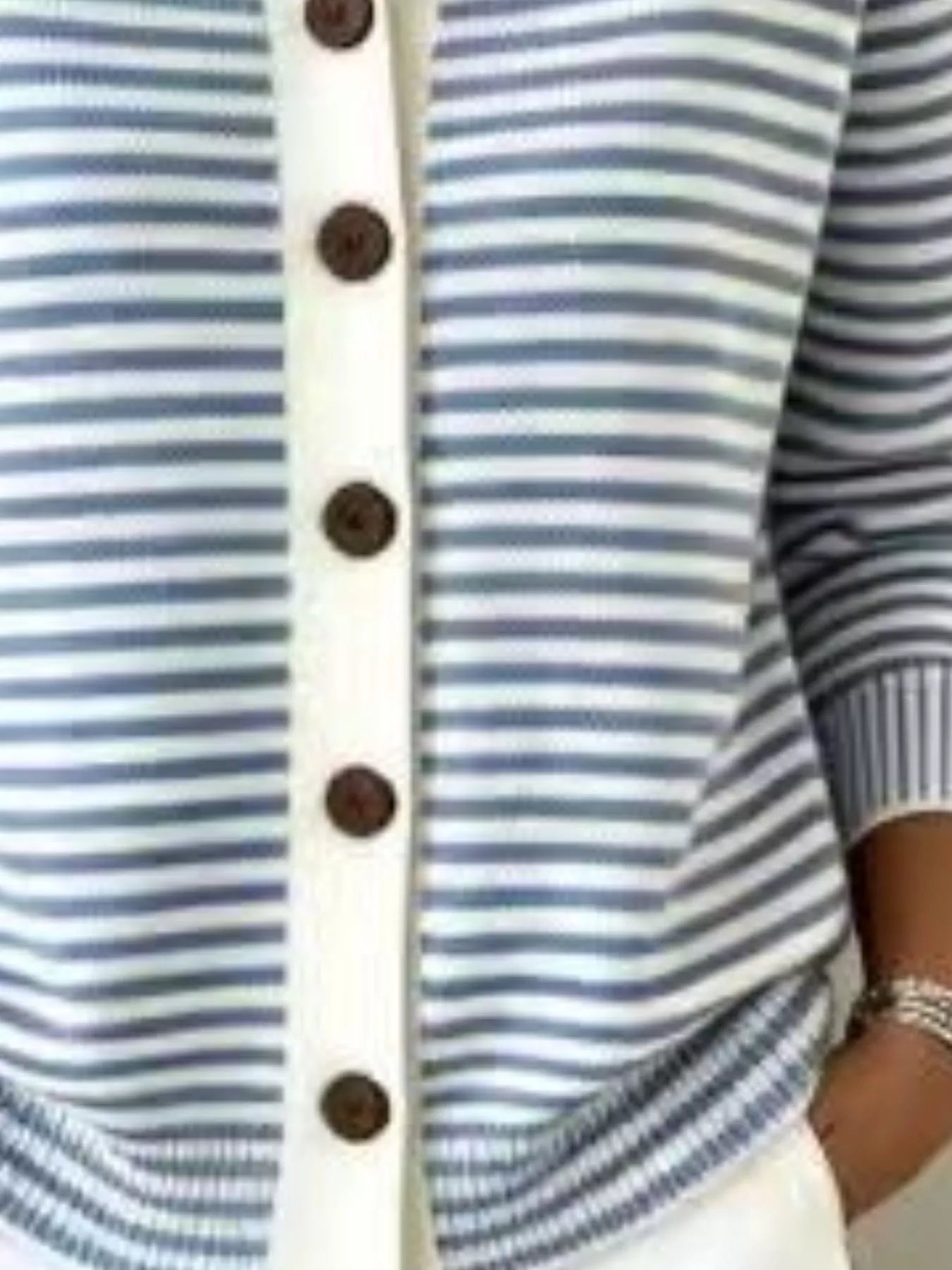 Close-up of the lower front and ribbed hem of a blue and white striped knit cardigan
