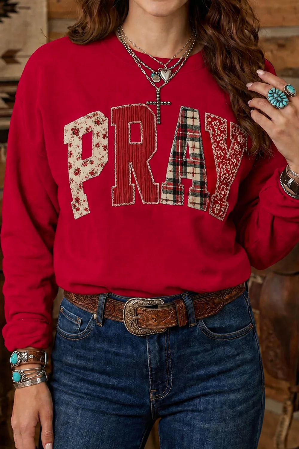 Scarlet western sweatshirt with patchwork PRAY lettering worn with jeans, front view