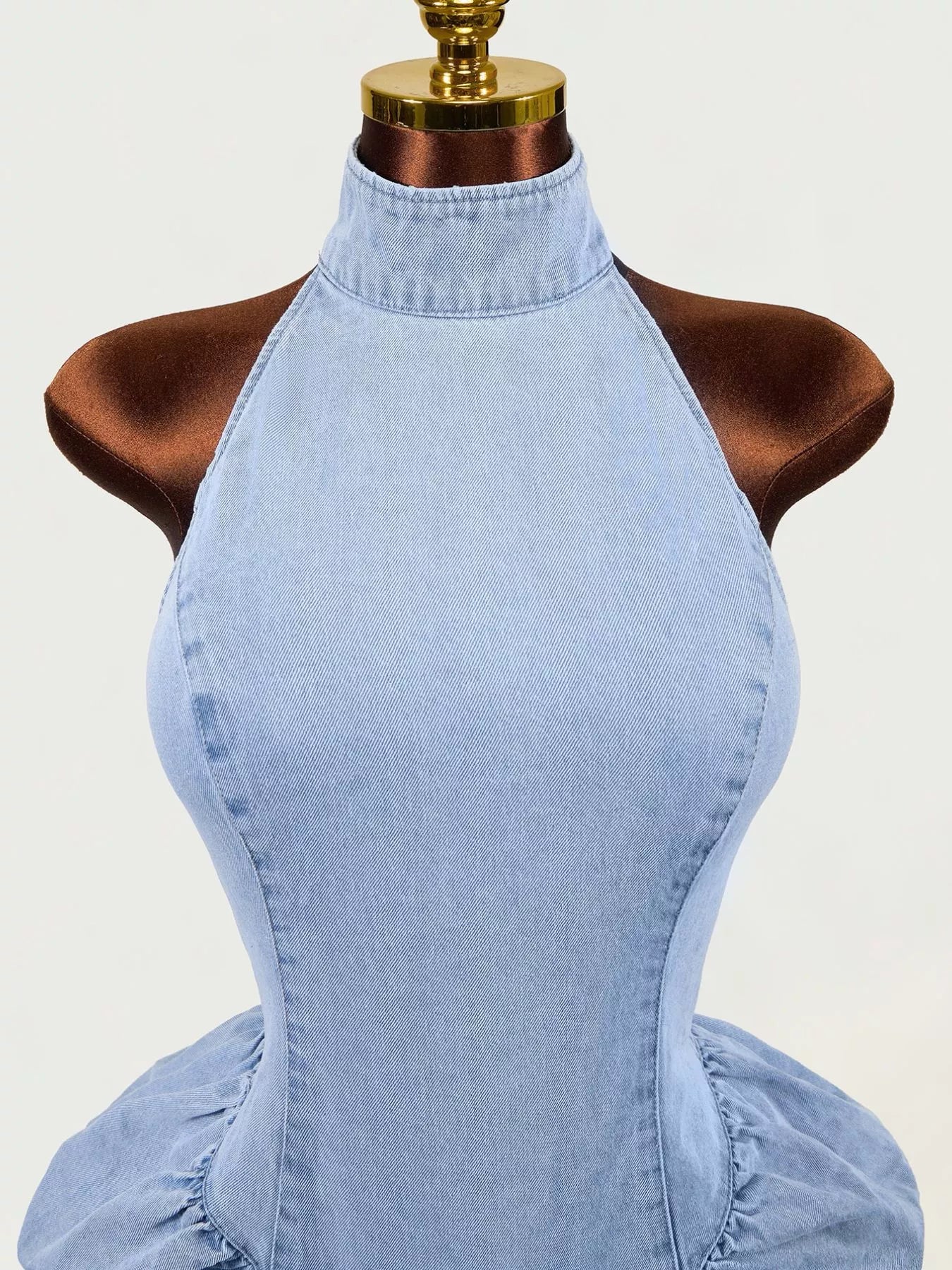 Close up of light blue sleeveless mock neck ruched bodycon denim dress bodice on mannequin