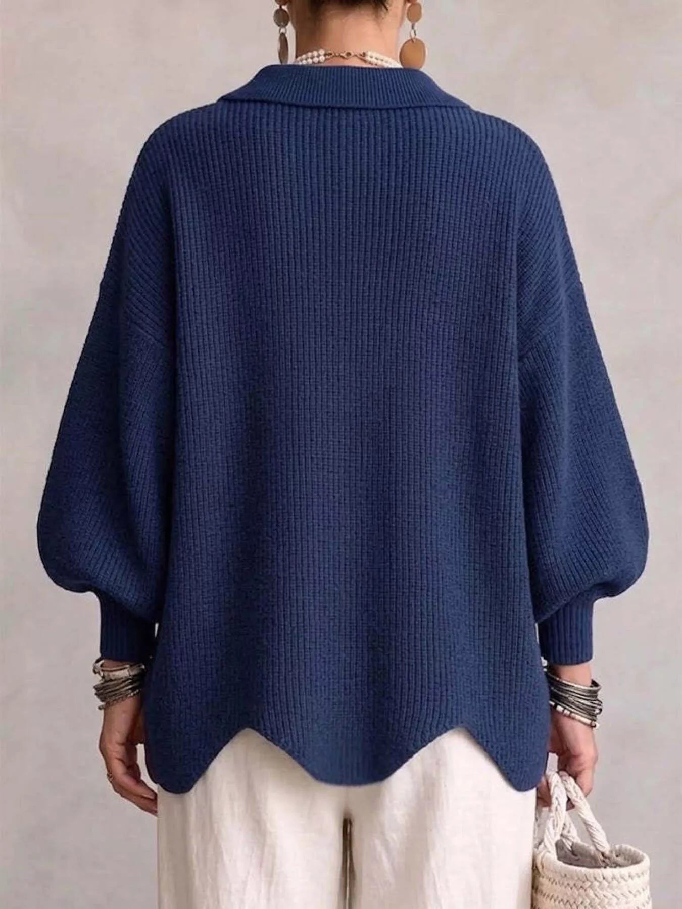 Back view of the navy knit cardigan with lantern sleeves and scalloped hem