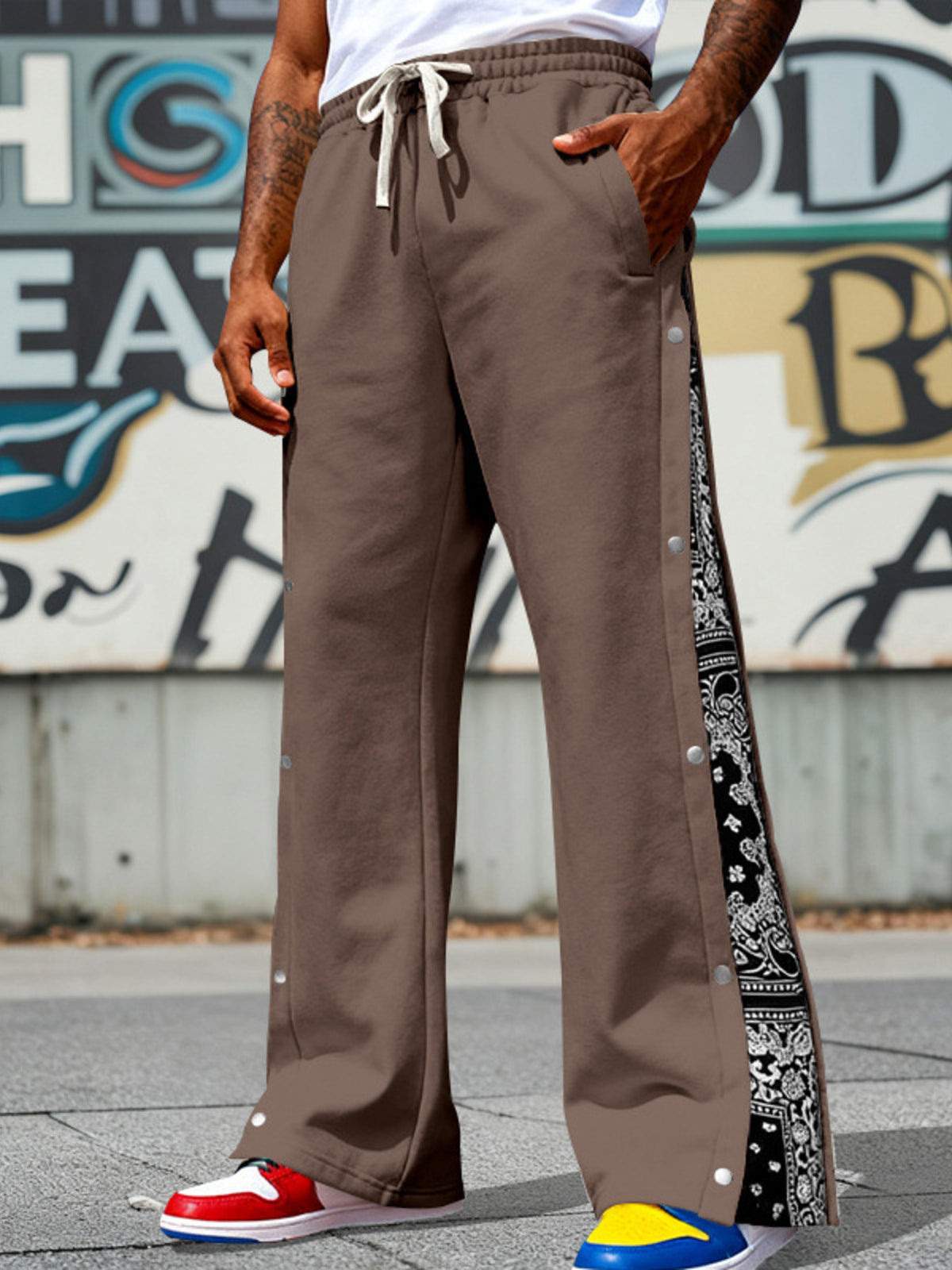 Men's dark brown wide-leg pants with side snaps and a drawstring waist.