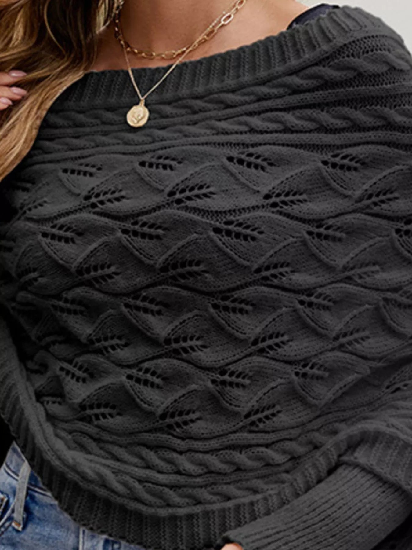 Close up of black batwing sweater neckline with cable and leaf openwork knit.
