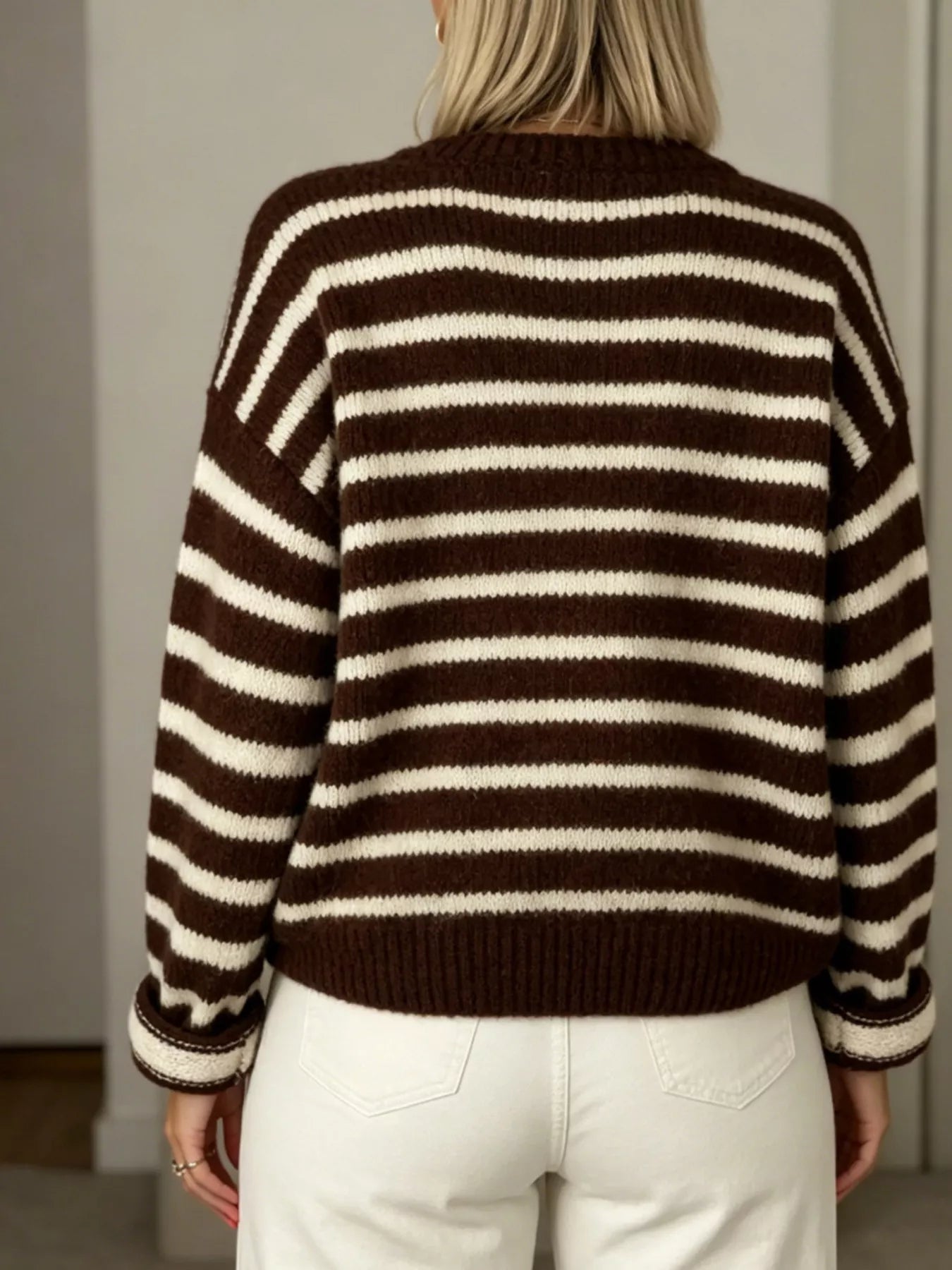 Back view of brown and white striped button down cardigan with long sleeves and white pants