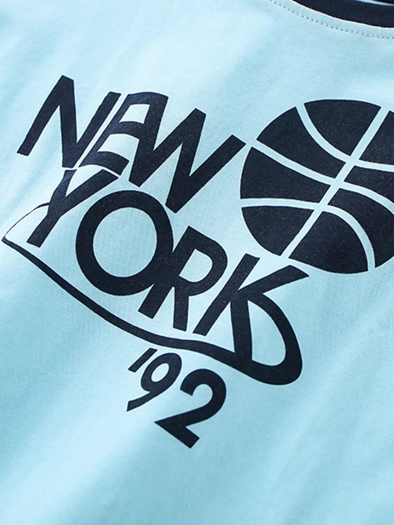 Close-up detail of the dark navy NEW YORK basketball graphic on pastel blue fabric