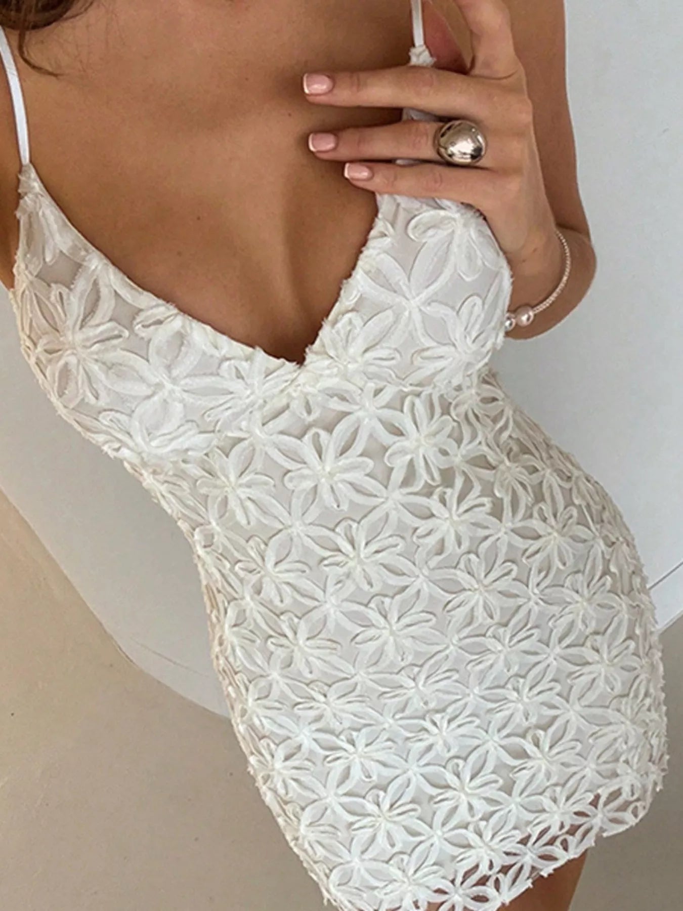 Close view of white floral lace bodice and V neckline of mini dress