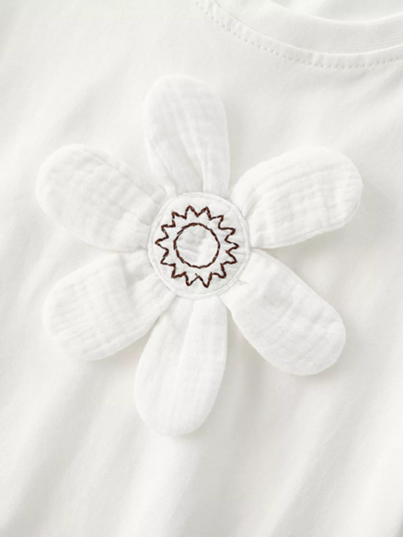 Close-up of padded white flower applique with stitched starburst center on white t-shirt