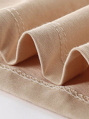 Close-up of the tan top hem showing neat stitching and soft folded fabric