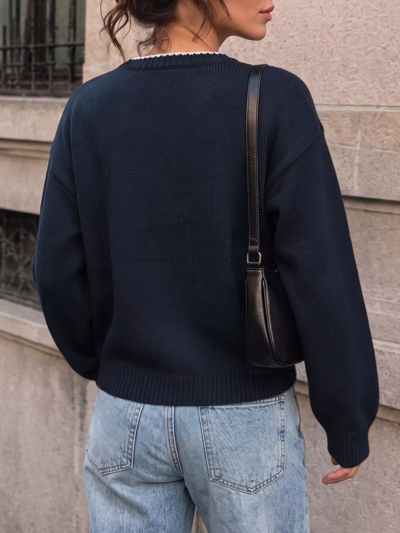 Back view of a plain navy sweater with white neck trim and ribbed hem
