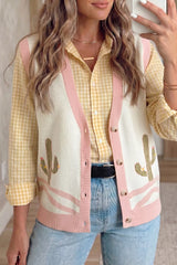 On-model front view of a cream cactus patterned sweater vest with pink trim over a check shirt