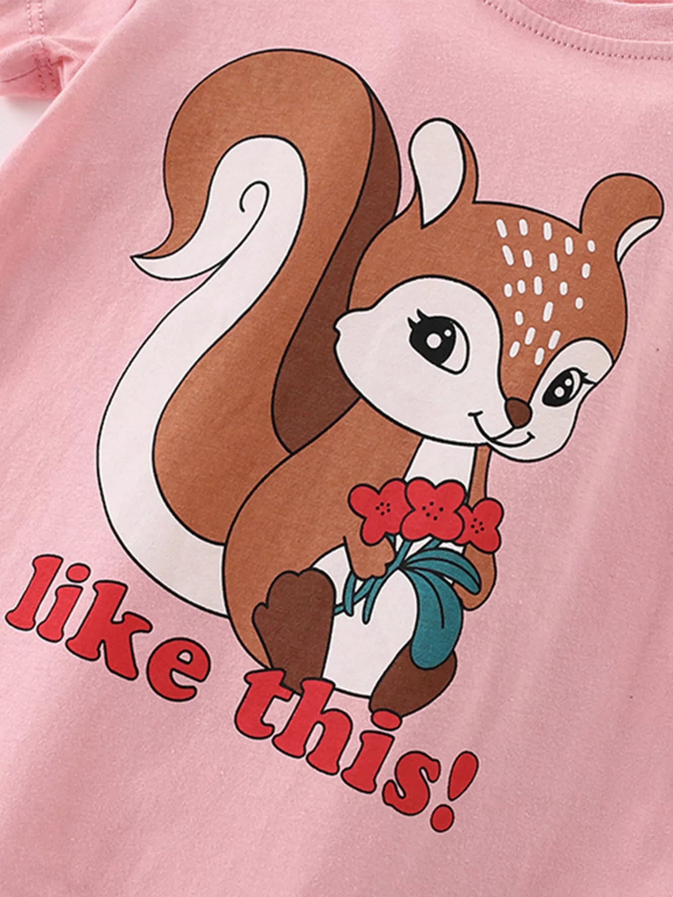 Angled close-up of squirrel holding red flowers on blush pink children's short sleeve t-shirt