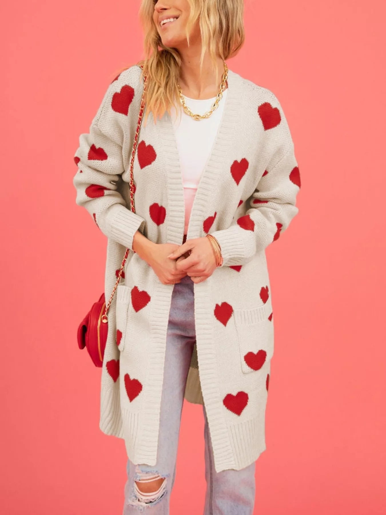 Front view of the cream heart print cardigan worn open with hands clasped