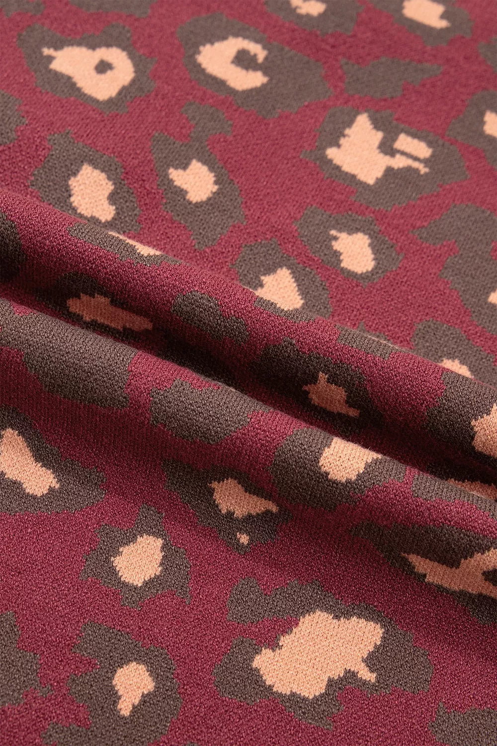 Close-up detail of deep red leopard print knit fabric