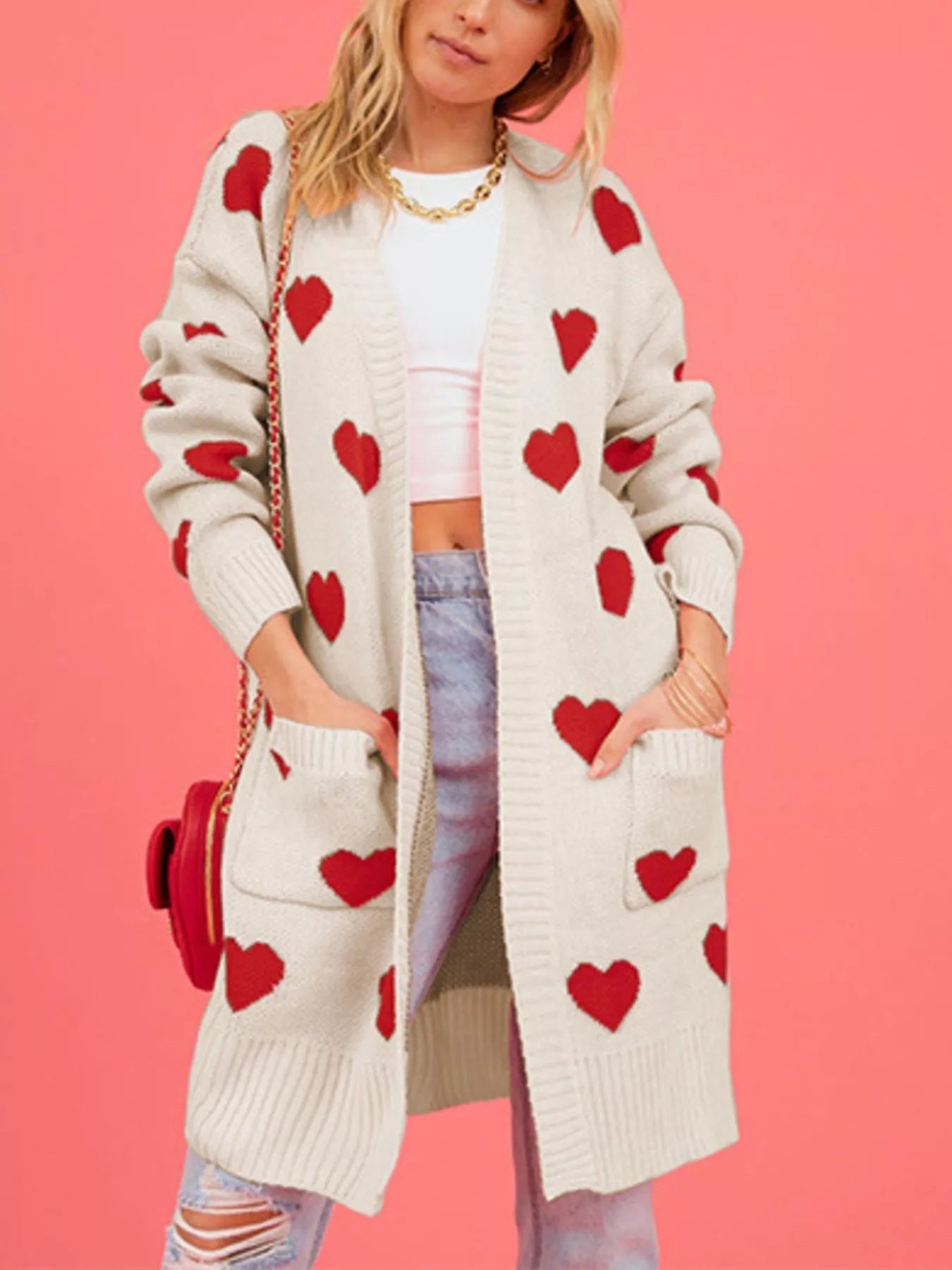 Front view of a cream longline cardigan with red hearts and patch pockets