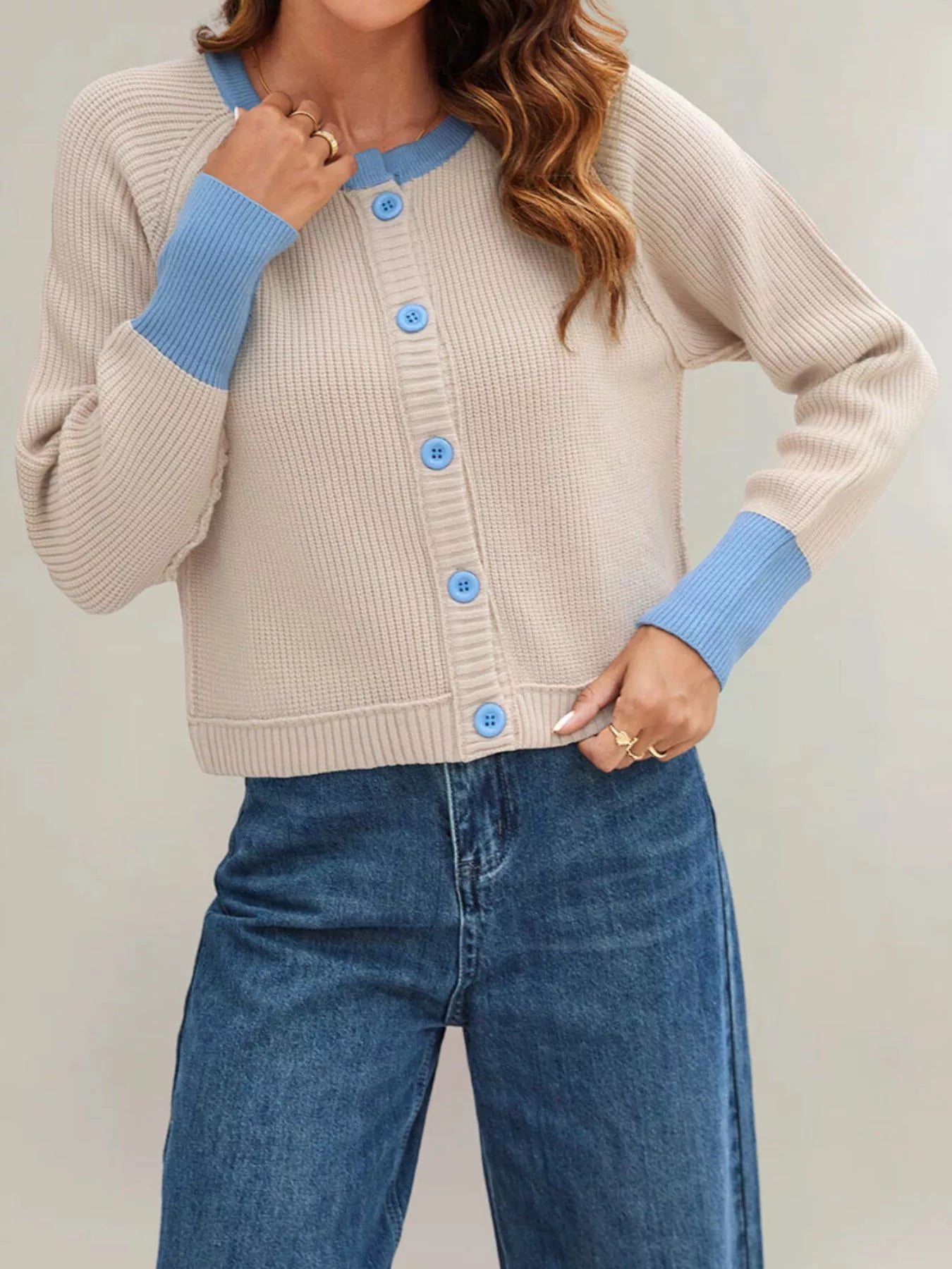 On-model front view of a beige ribbed cardigan with light blue trim and matching buttons
