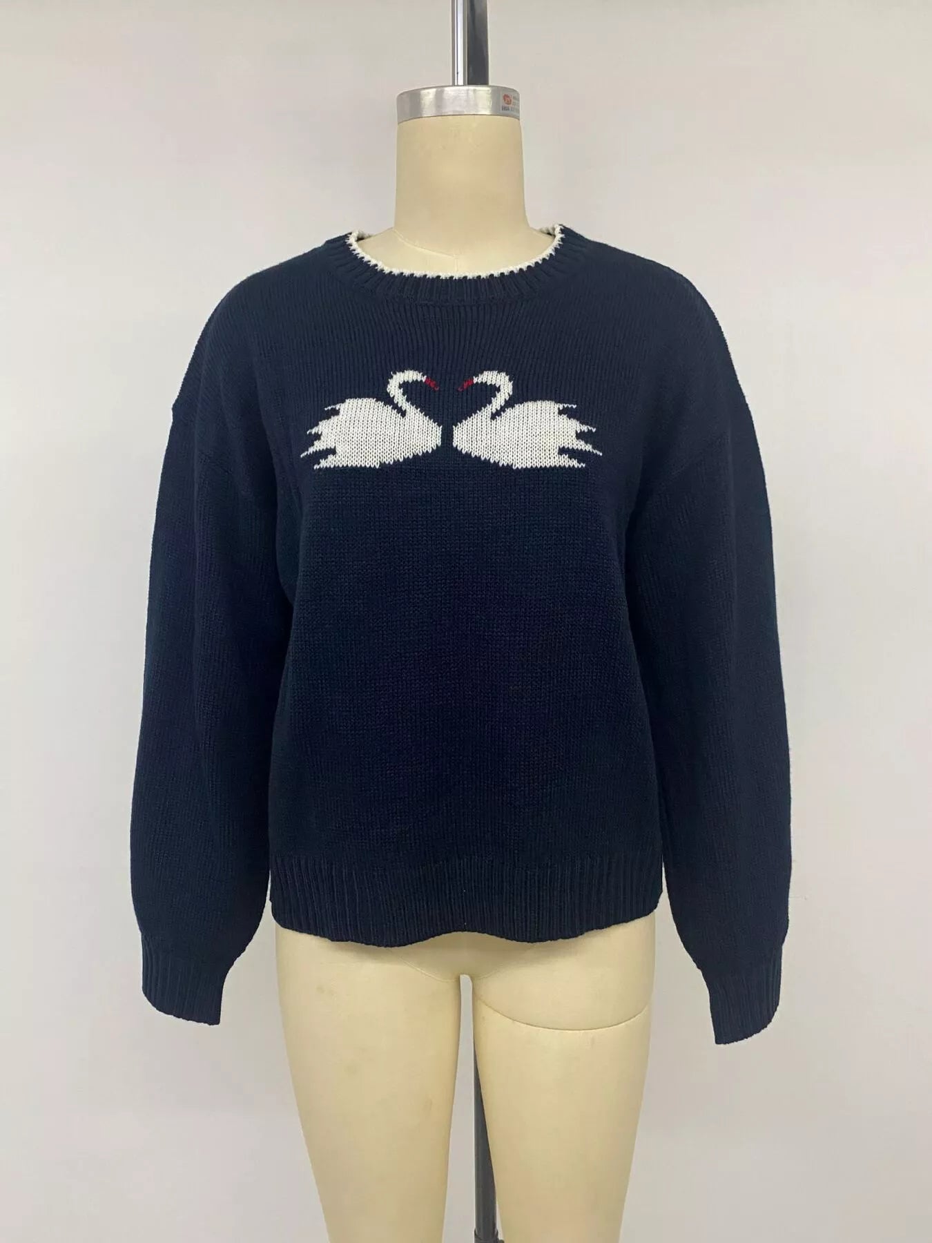 Front view on a mannequin of a navy sweater with white swan pair motif