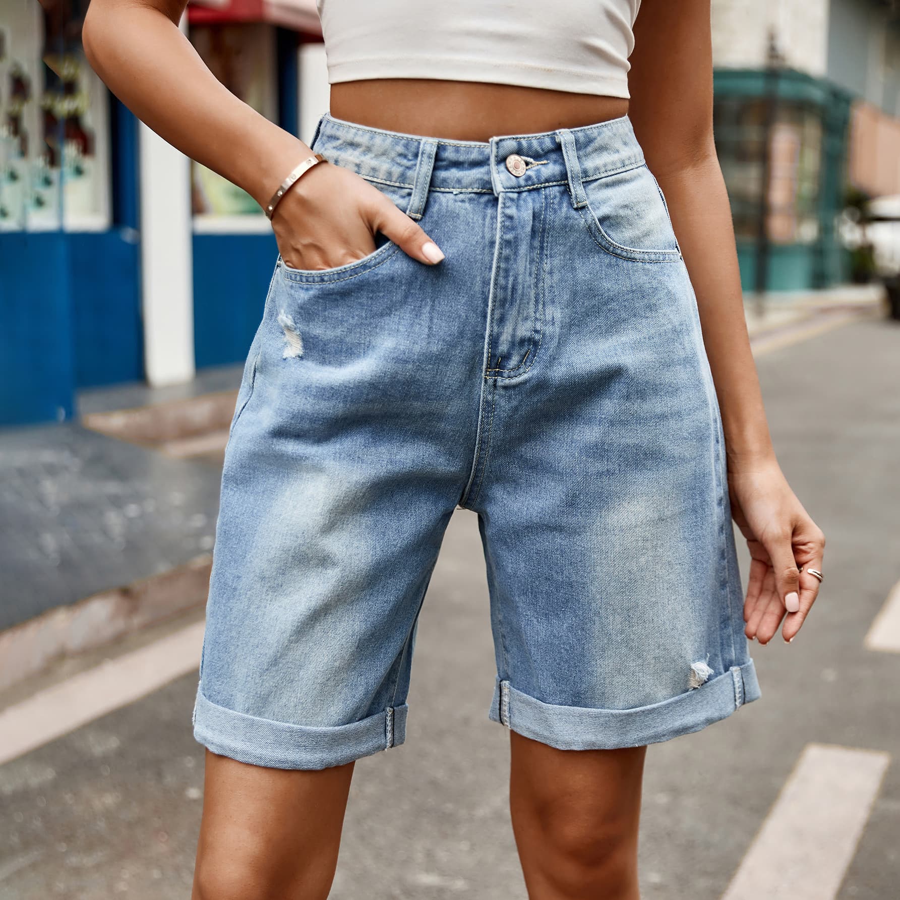Women's distressed denim shorts with buttons and pockets.