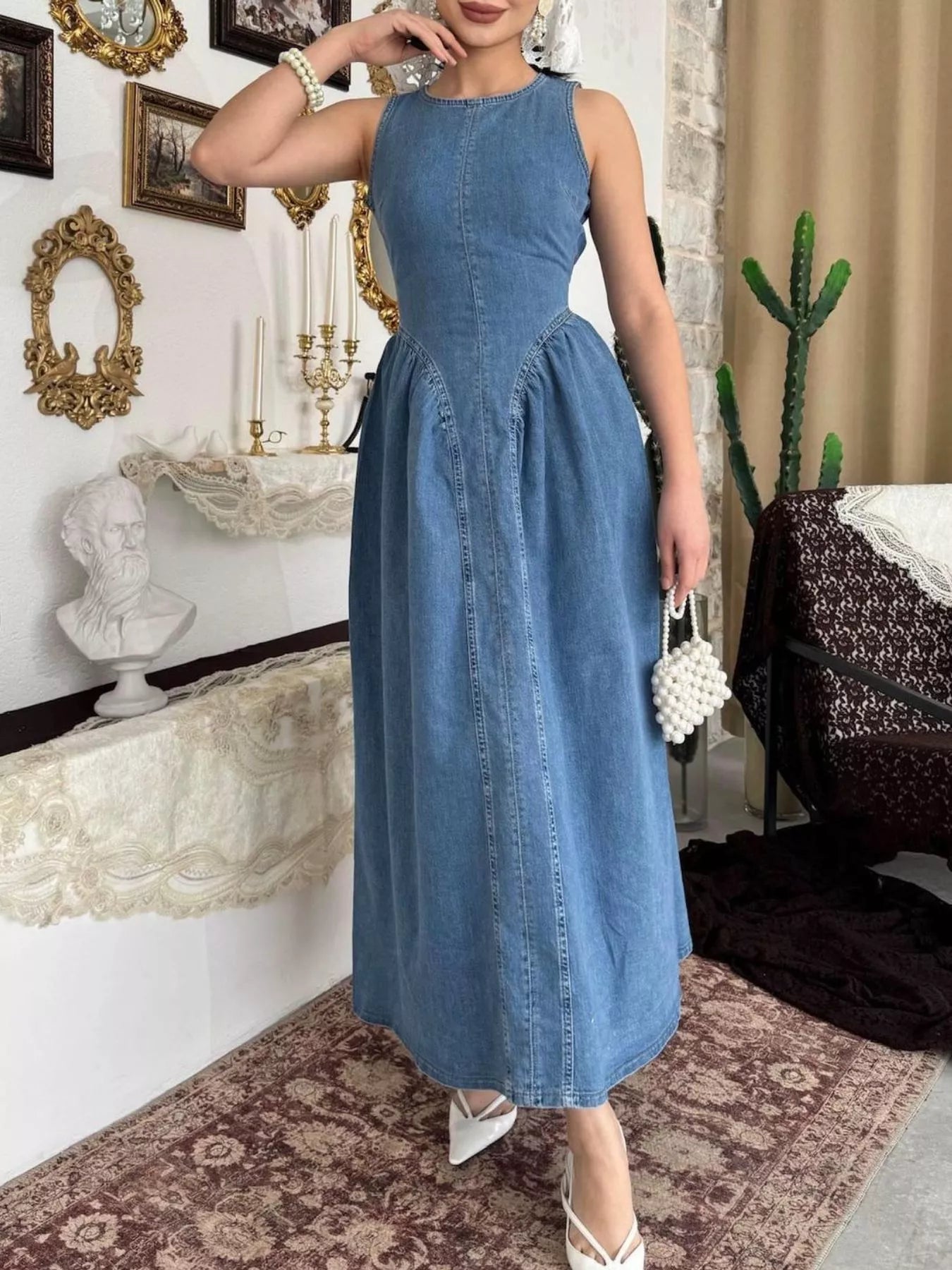 Dark blue sleeveless denim midi dress with fitted bodice and flared skirt, front view indoors