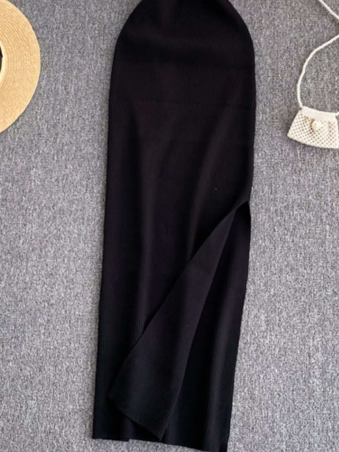 Lower skirt of black ribbed knit midi dress showing side slit detail