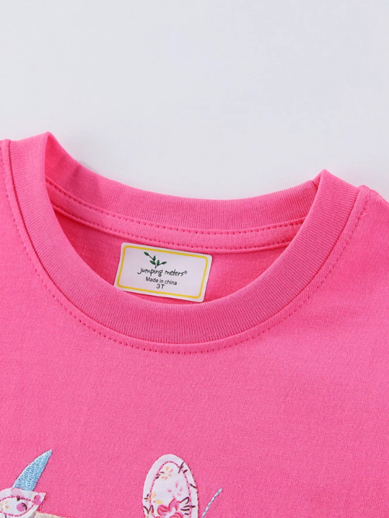 Close-up of ribbed crew neckline and inner label on fuchsia pink children's tee