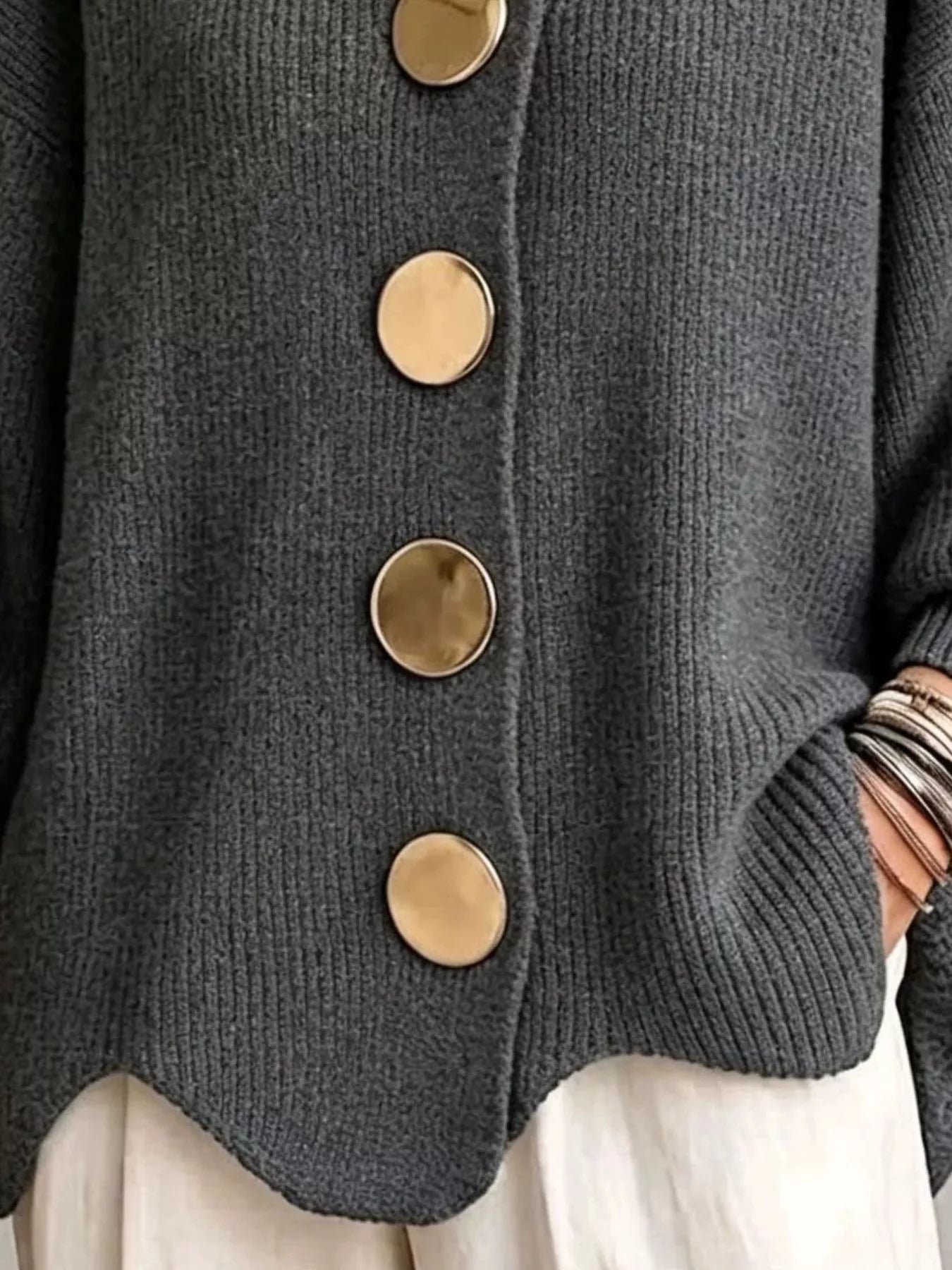 Close up of the dark gray cardigan gold buttons and scalloped hem