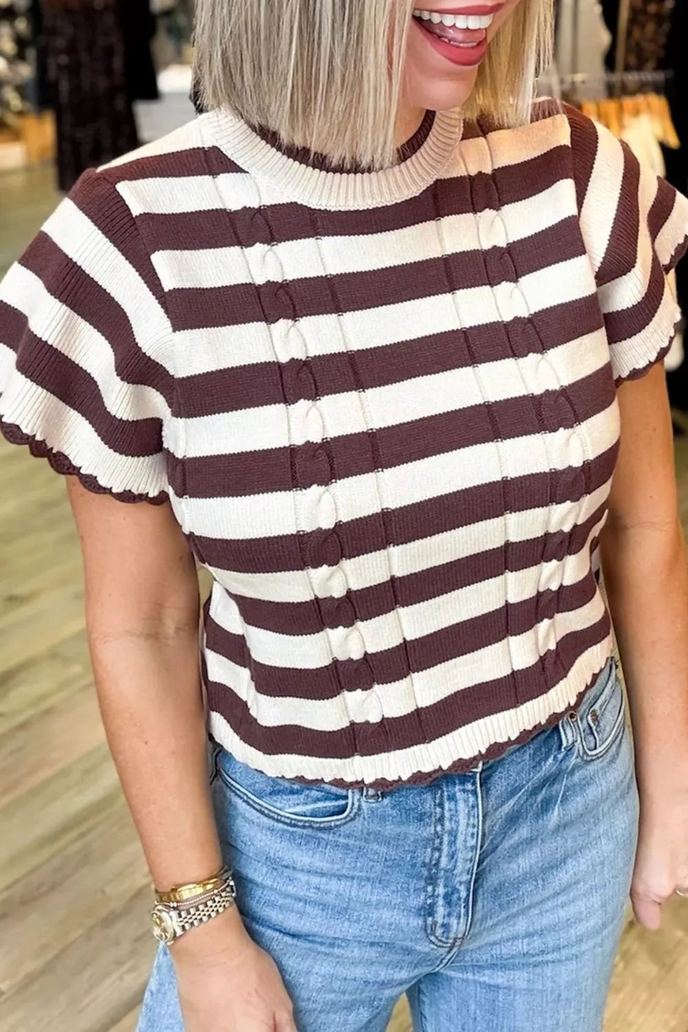 Closer front view of brown and cream striped cable knit sweater showing ribbed round neckline.