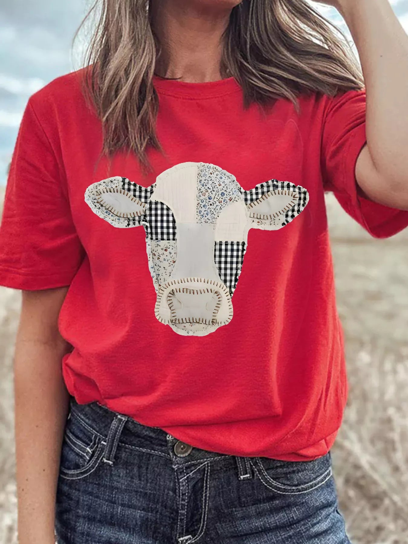 Front view of deep red round neck casual top with patchwork cow print worn outdoors
